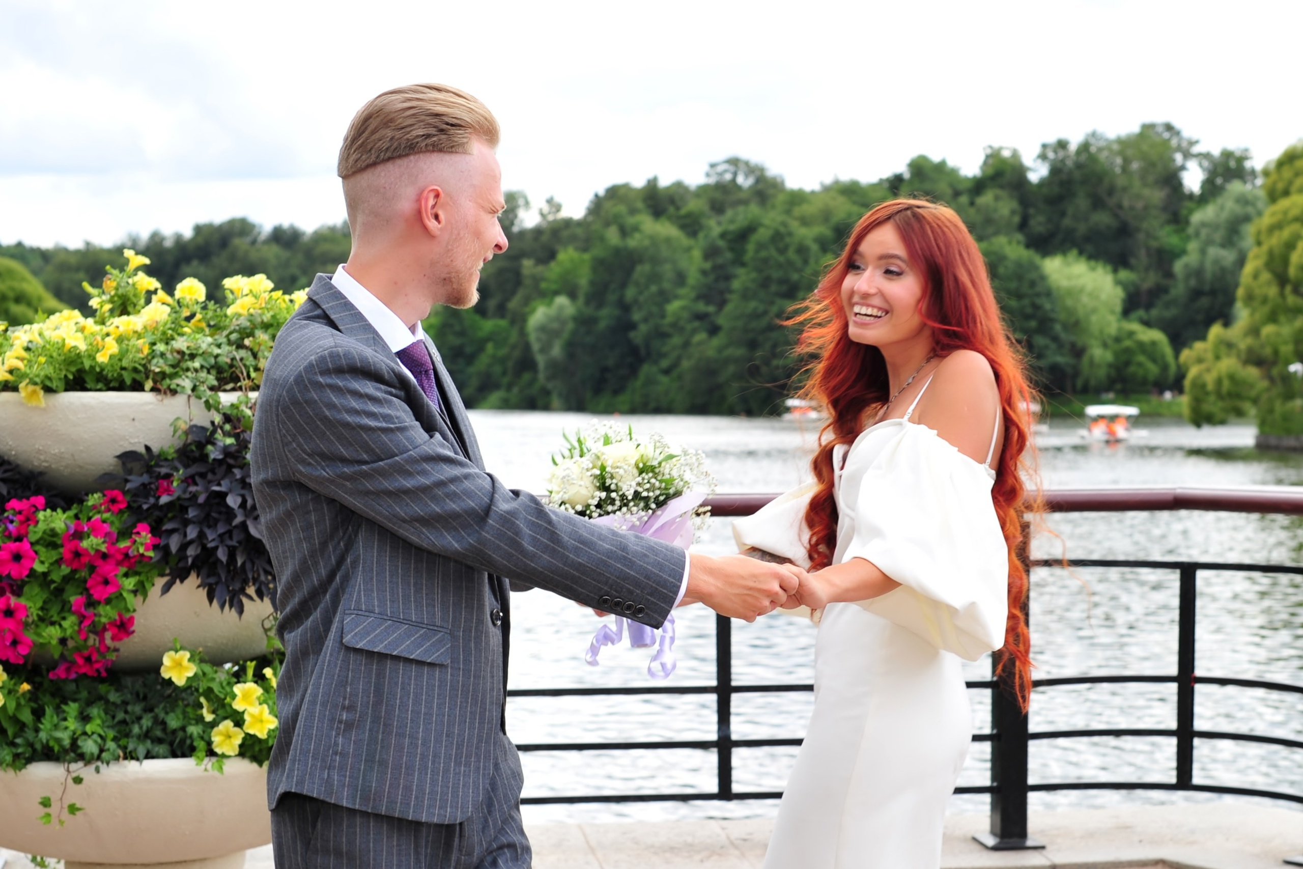 Свадьба в Царицыно летом, жених и невеста держатся за руки и смотрят друг на друга на фоне пруда