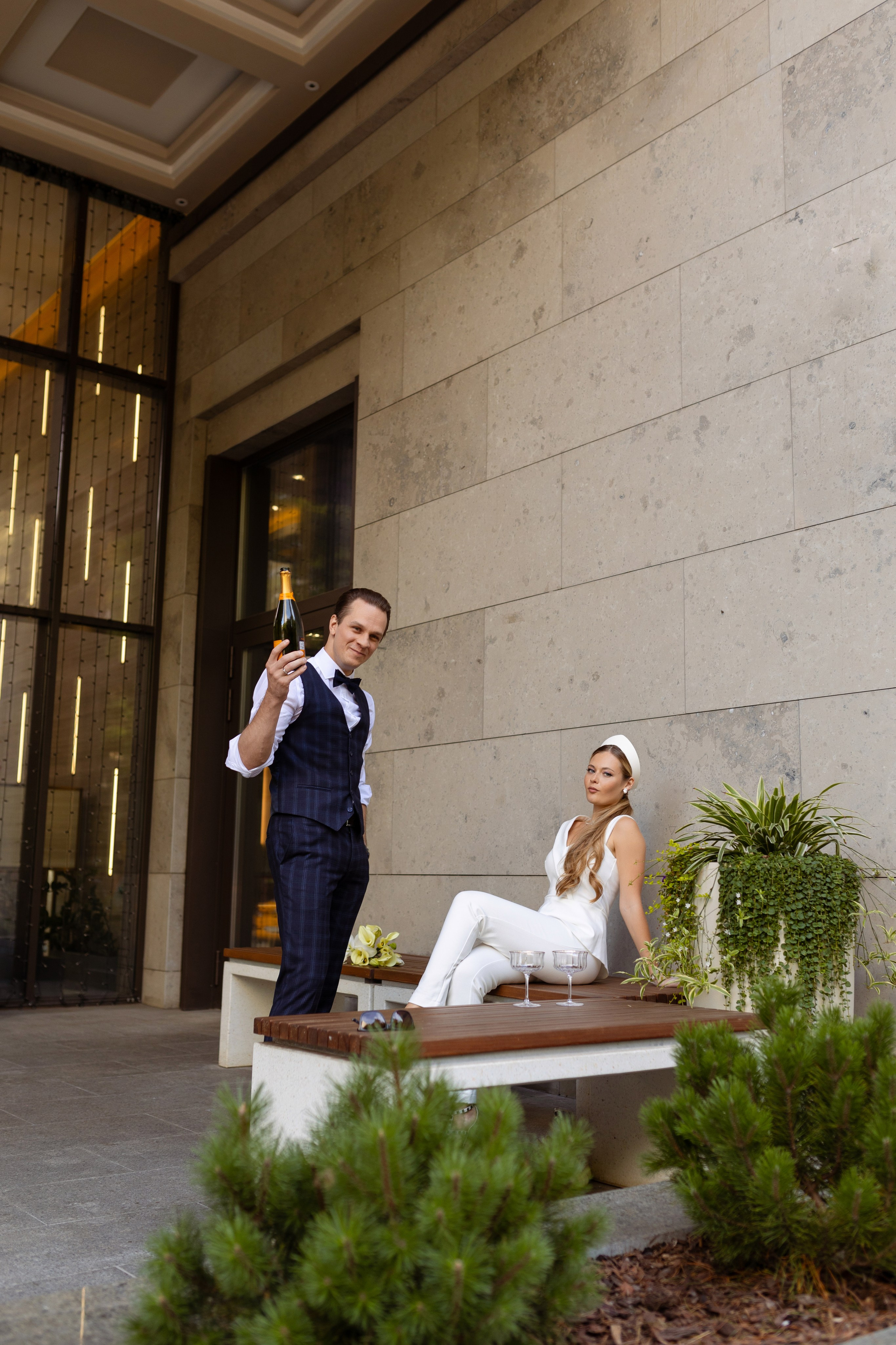 Жених  машет в объектив правой рукой.