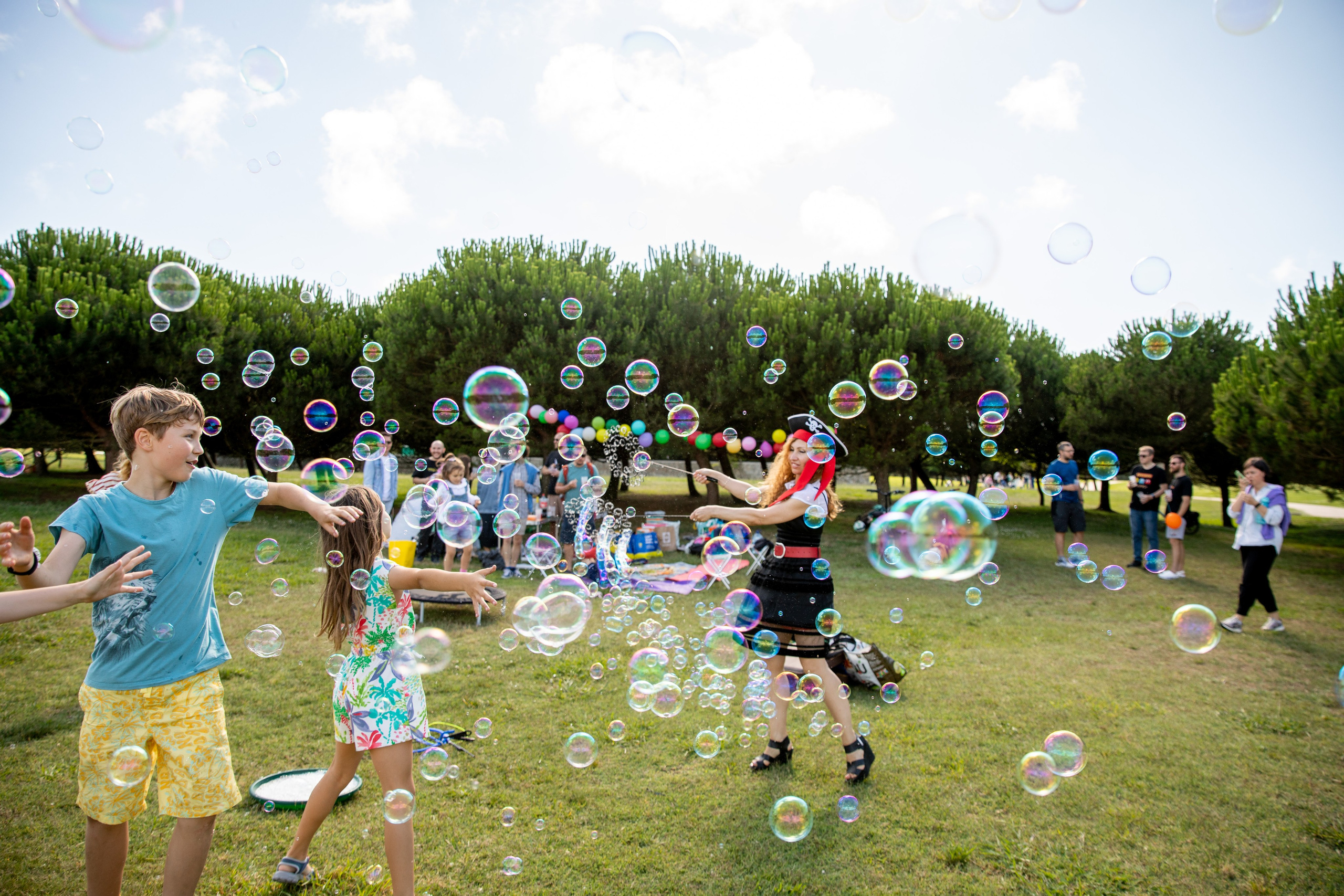 Happy kids playing in the park with soap bubbles at a birthday celebration photo shoot. Children's and Family Photographer Oksana Lomnova
