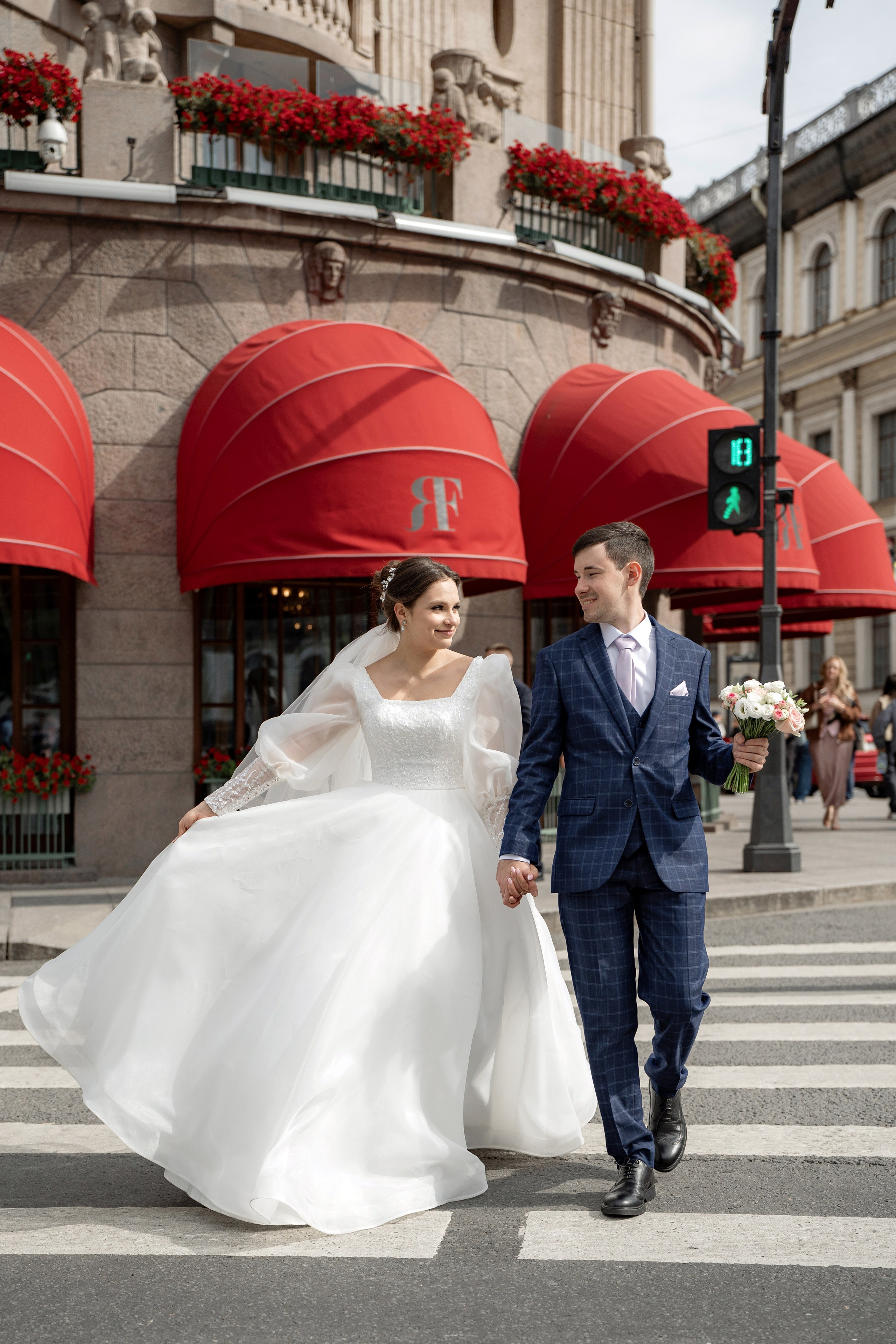 жених и невеста идут по пешеходному переходу гостиницы Астория. Свадебная фотосессия у Астории на Исаакиевской площади.