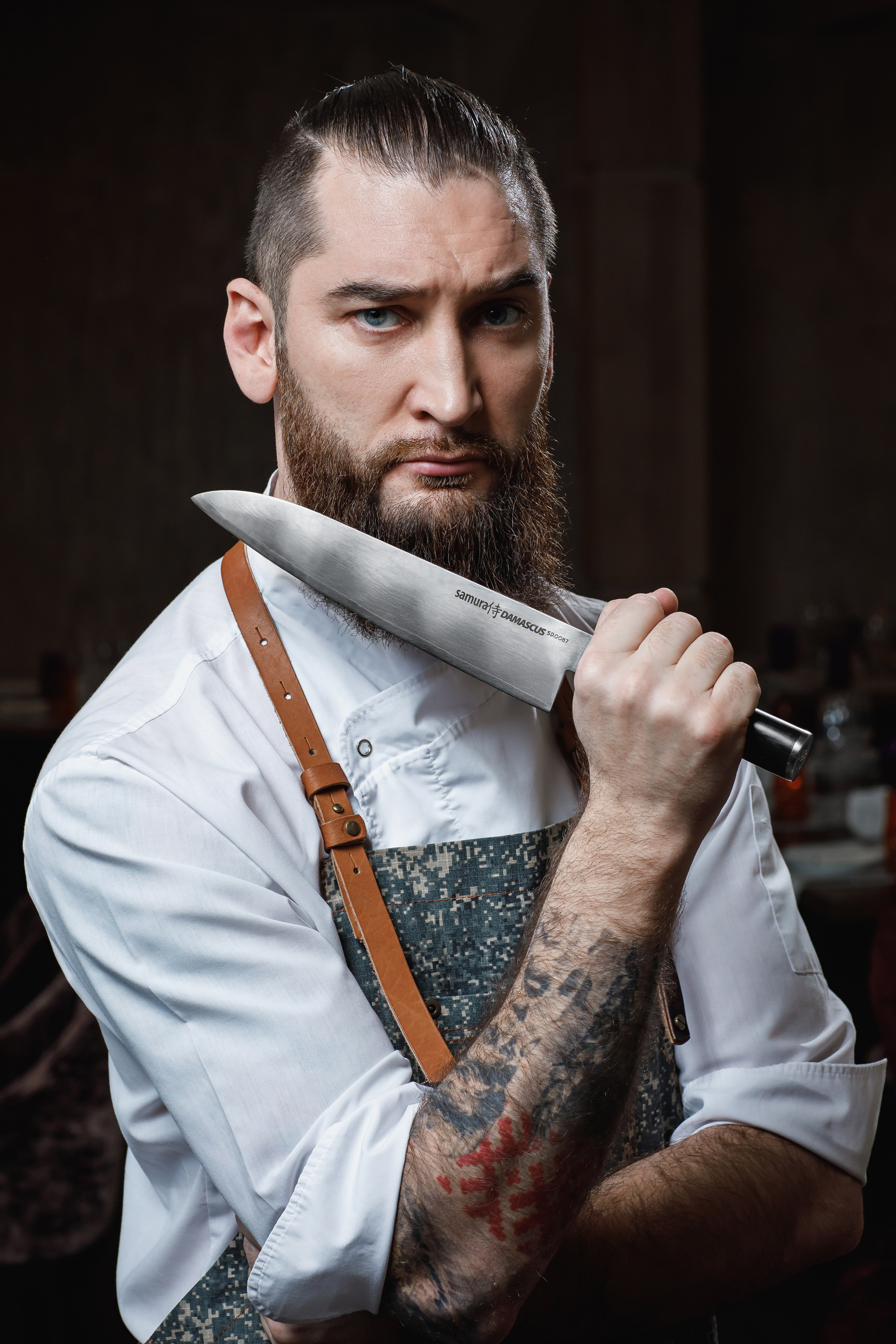 Портрет брутального мужчины-повара, который держит в руках профессиональный нож.