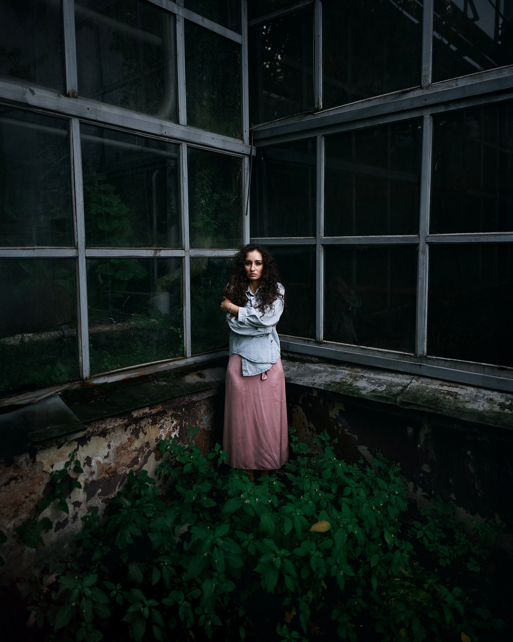 Девушка в платье стоит на фоне зелени