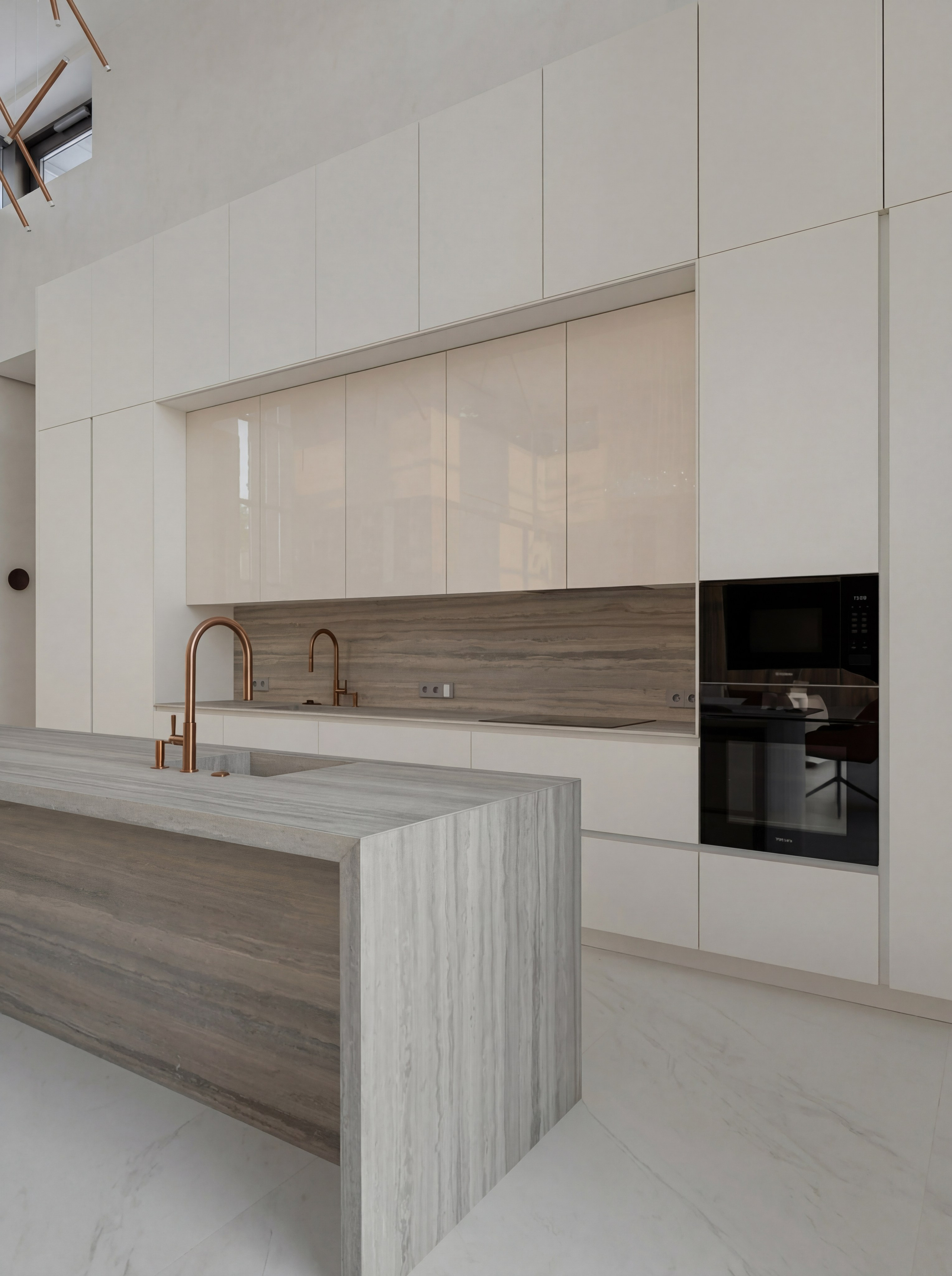 Детальный вид кухни от Валерии Котович: кухонный остров и фартук из серого камня, белые минималистичные шкафы до потолка и медные смесители в интерьере дома у воды.