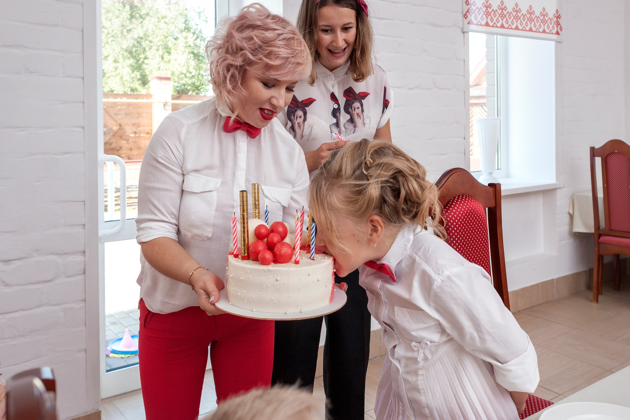 Девочка откусывает торт на своём дне рождения