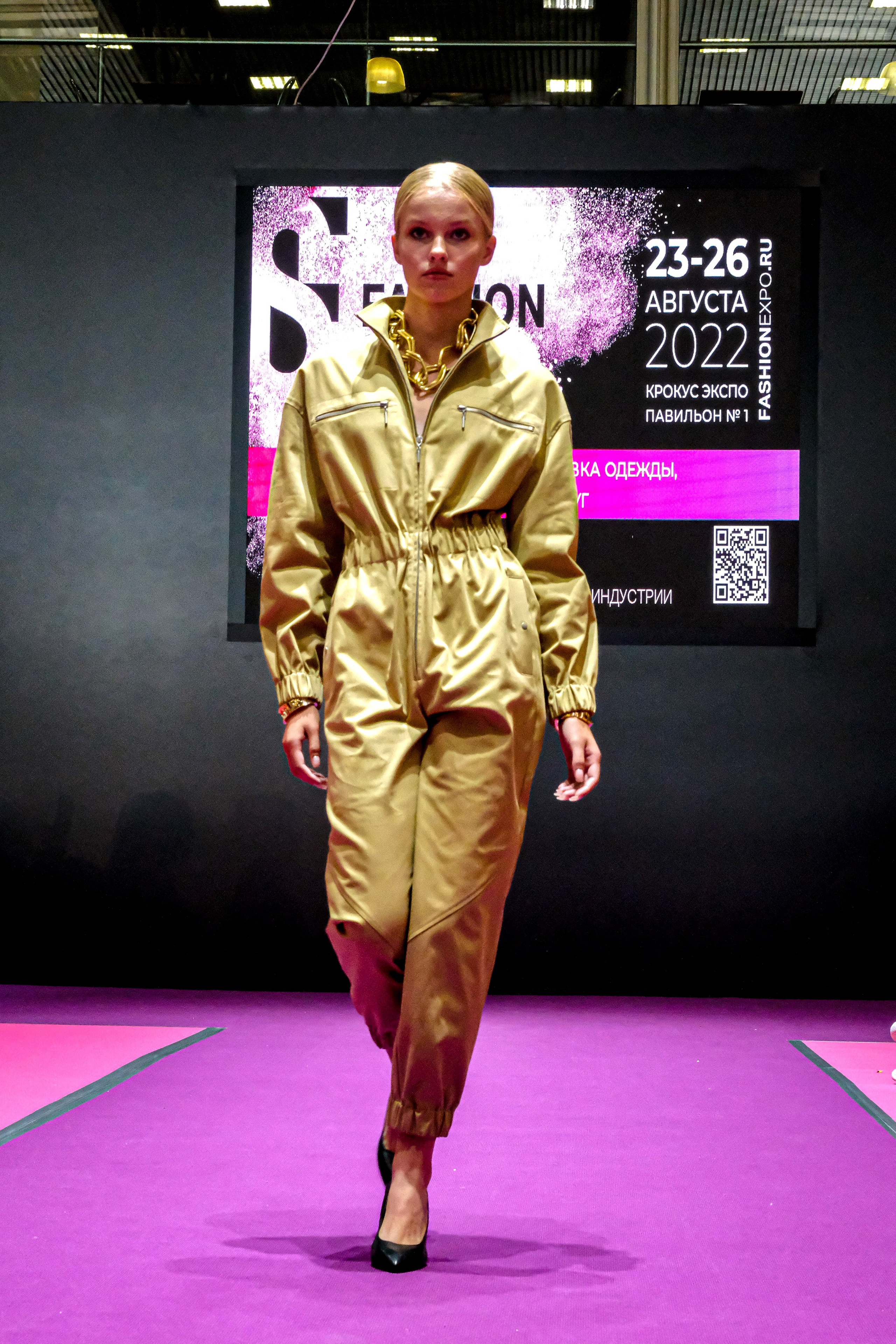  "Модели в ярких нарядах проходят по подиуму во время показа мод, освещенные яркими софитами и окруженные восторженными зрителями."