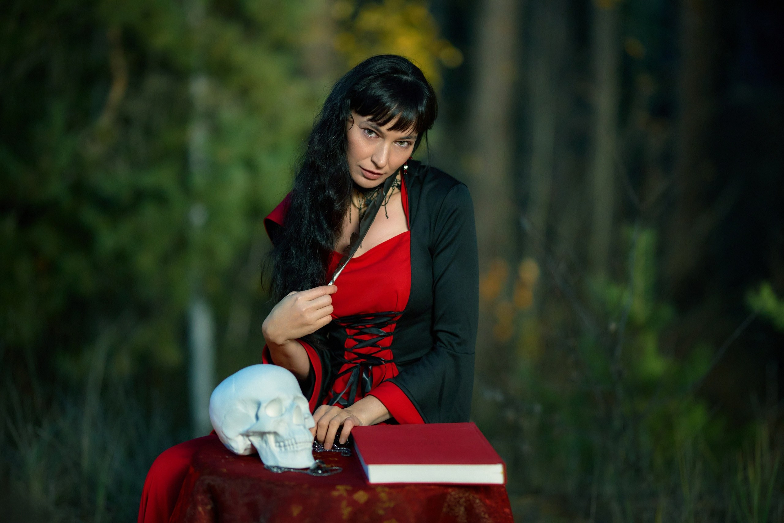 Колдунья сидит за столом с черепом что-то пишет в колдовской книге