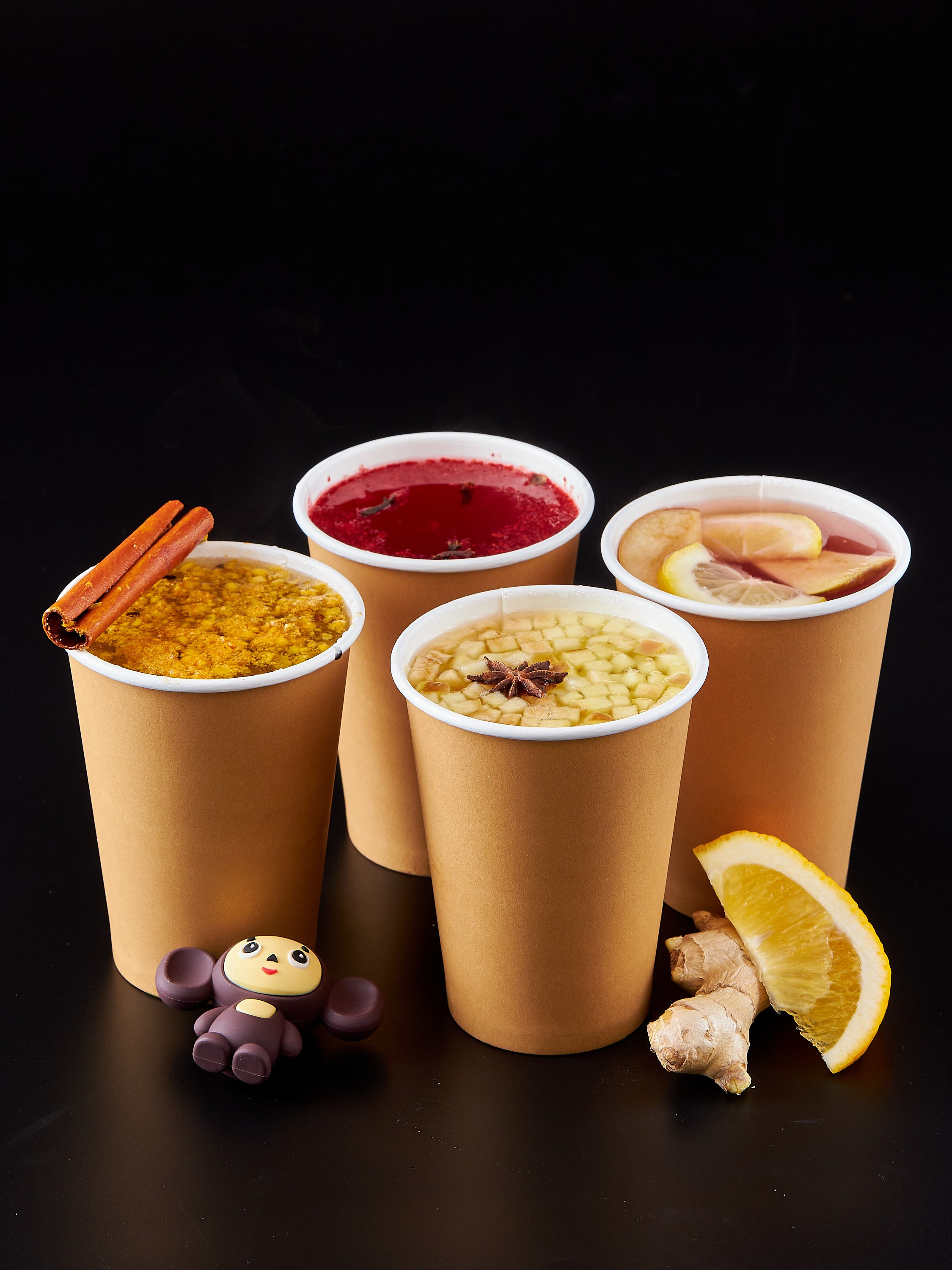 Коктейли в четырех бумажных стаканах на черном фоне