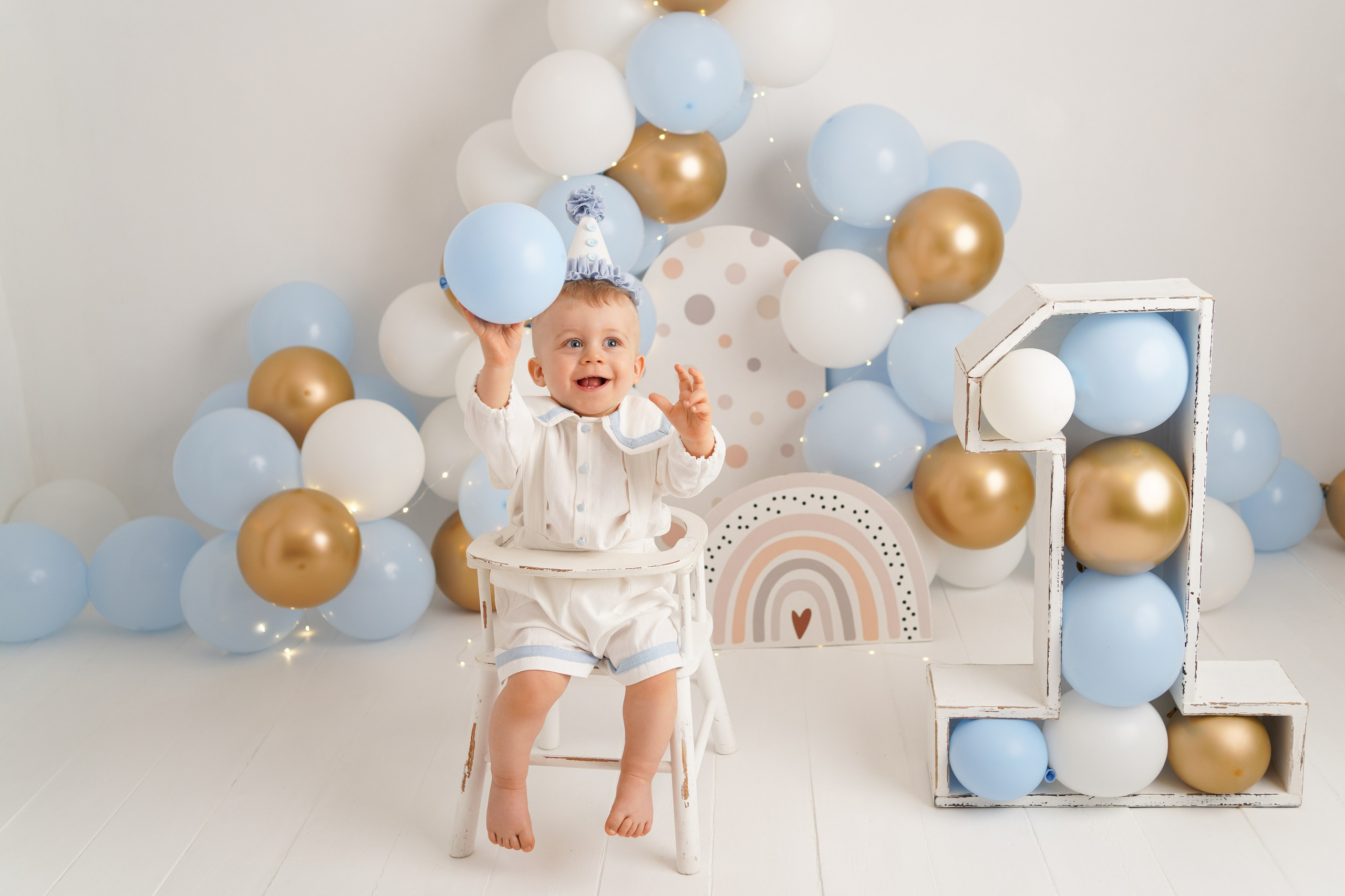 На фото малыш в колпачке и красивом костюмчике, вокруг много шариков. Это фотосессия Первый годик.