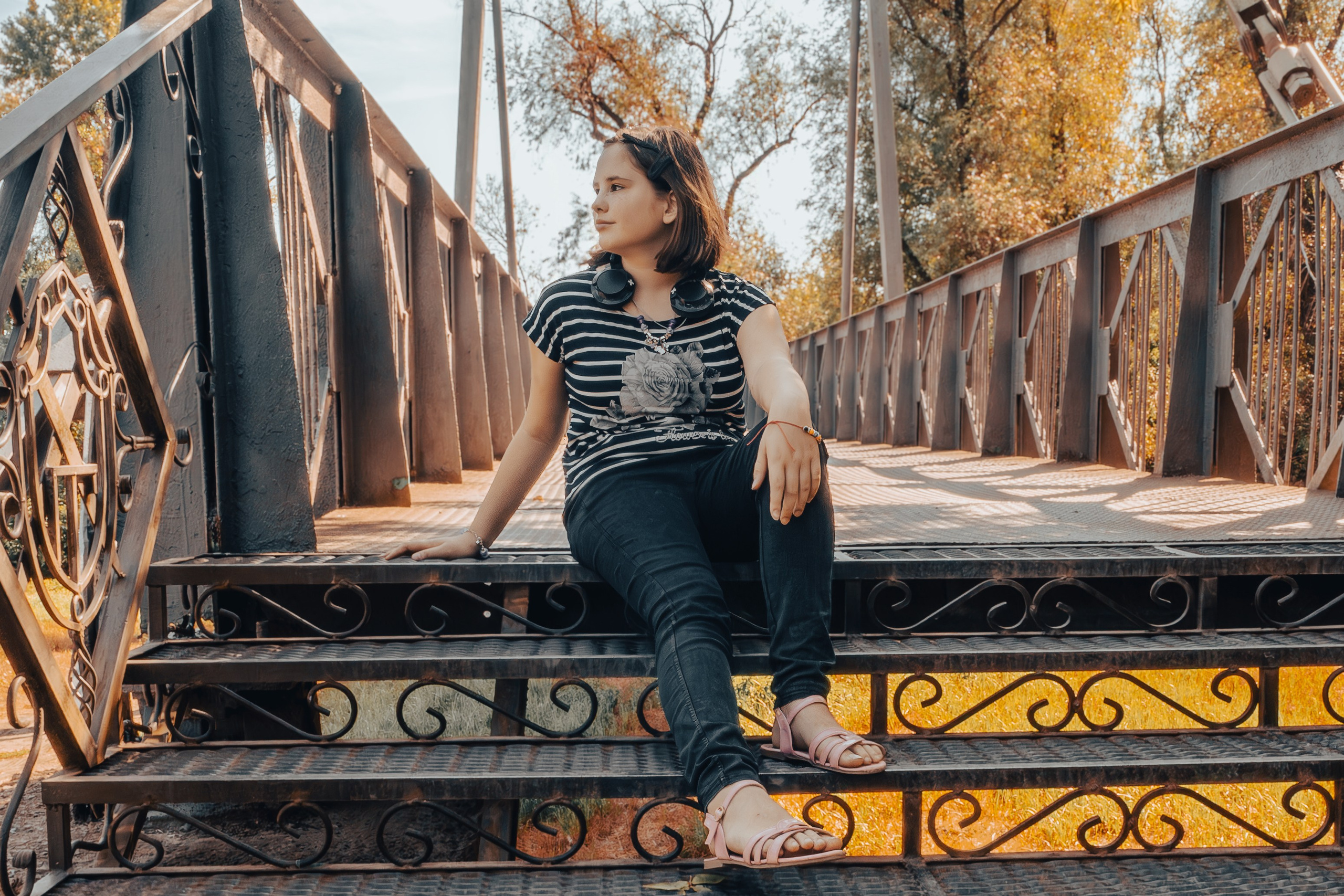 Девочка сидит на металлической ступеньке моста , девочка сидя на ступеньке вполоборота смотрит вдаль