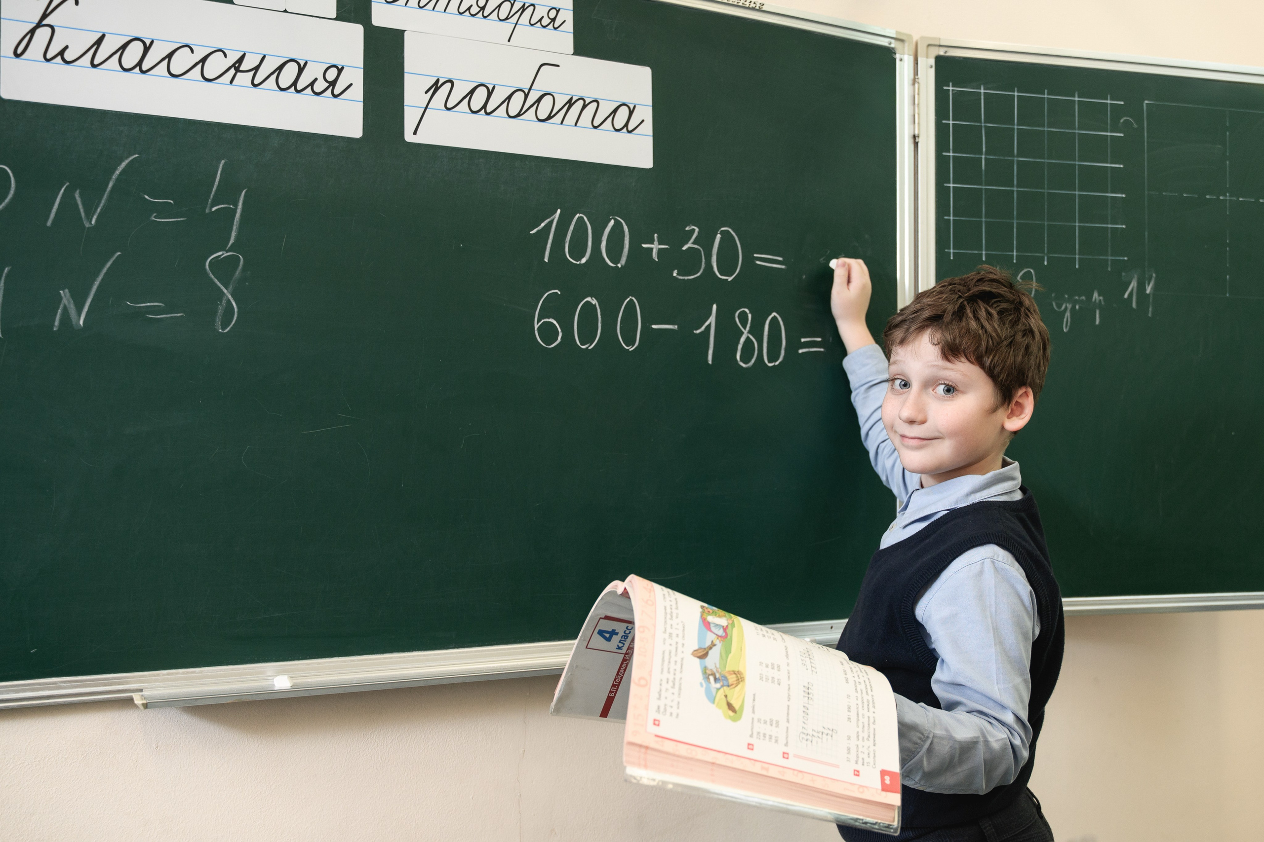 Ученик у доски решает пример на уроке математики
