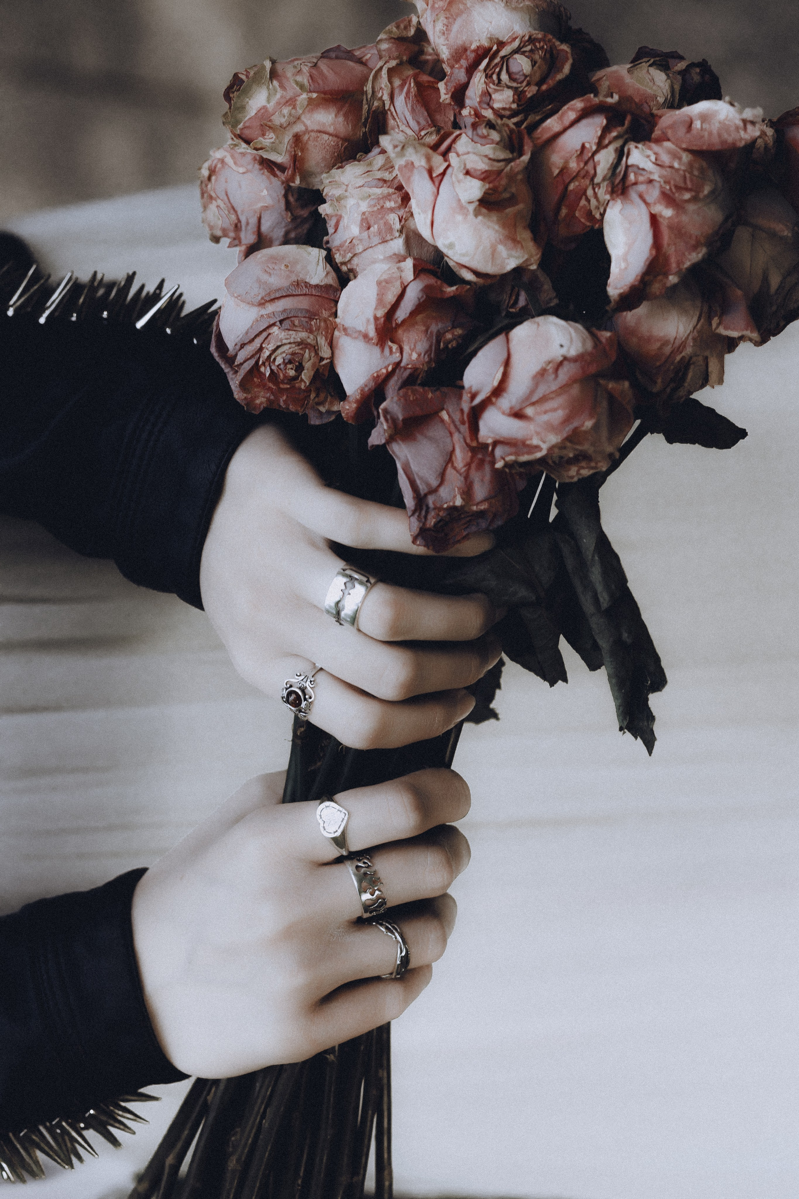Фотограф Александра Овечкина Пенза: крупный план рук с кольцами, держащих увядший букет роз, символизм в готике.