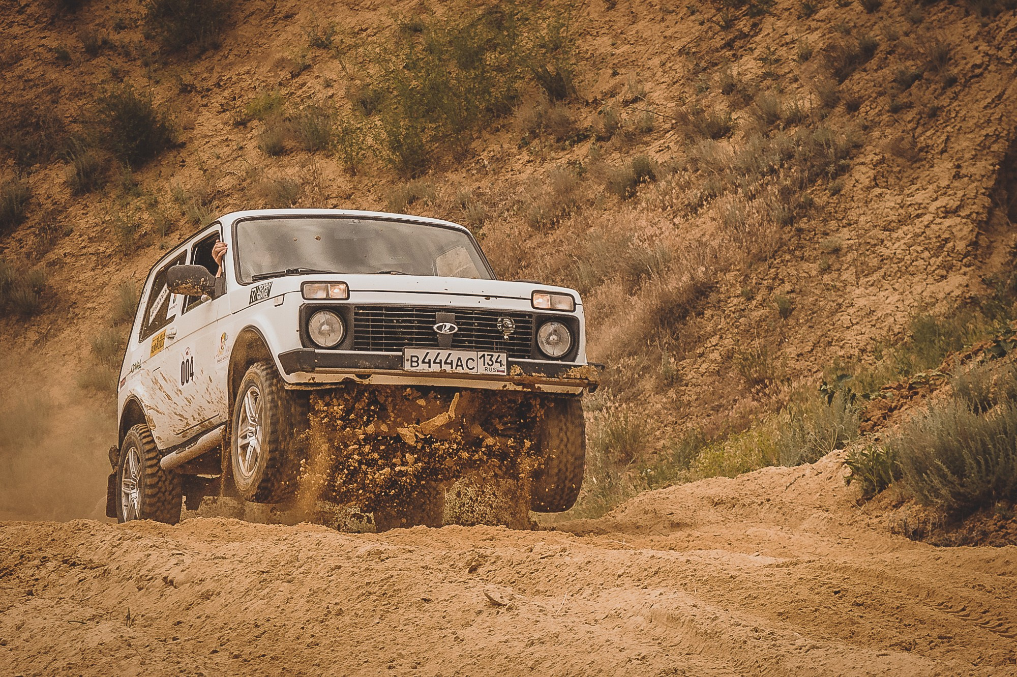 Белый автомобиль Нива взлетает на гору во время гонки