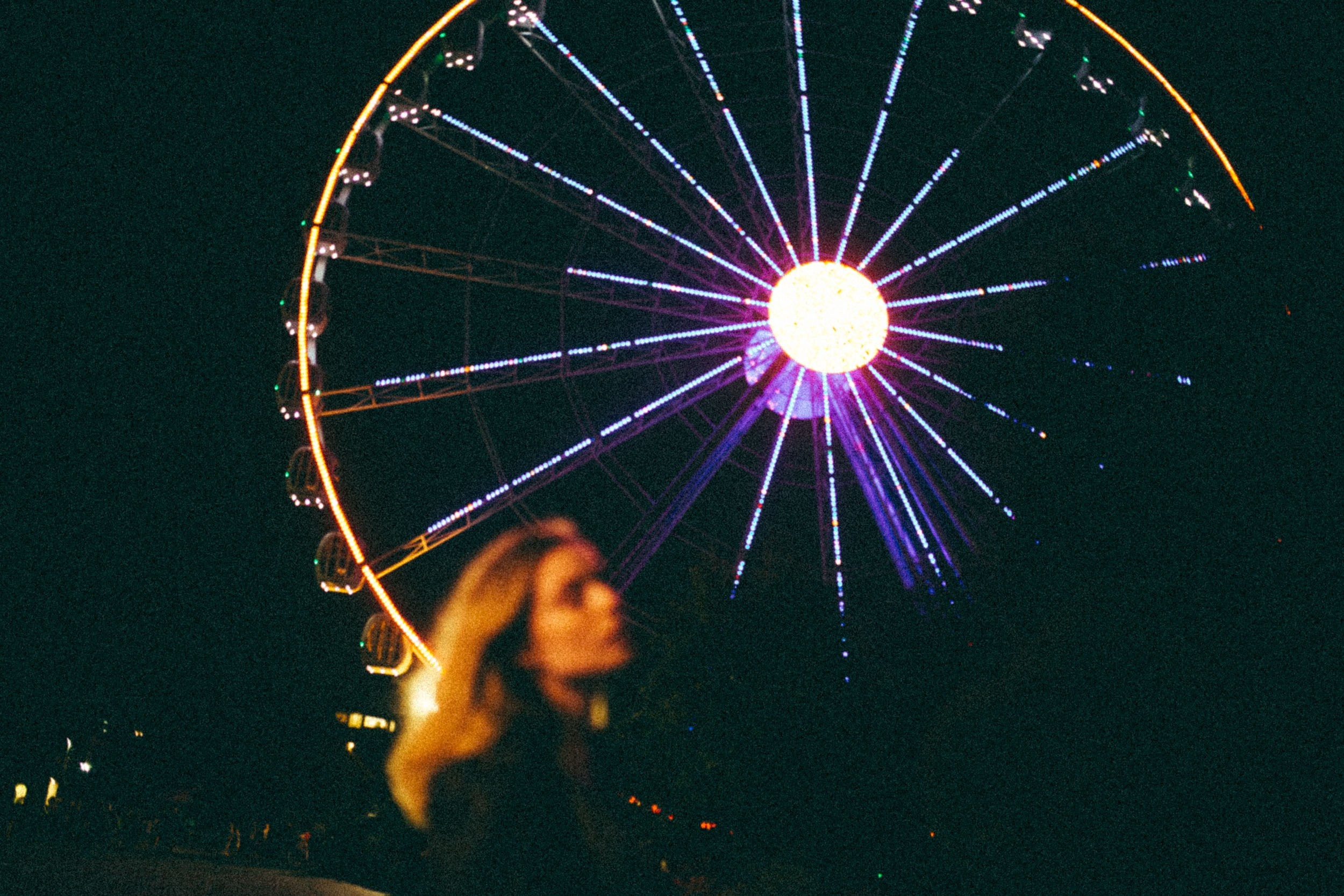 Блондинка на фоне светящегося колеса обозрения ночью