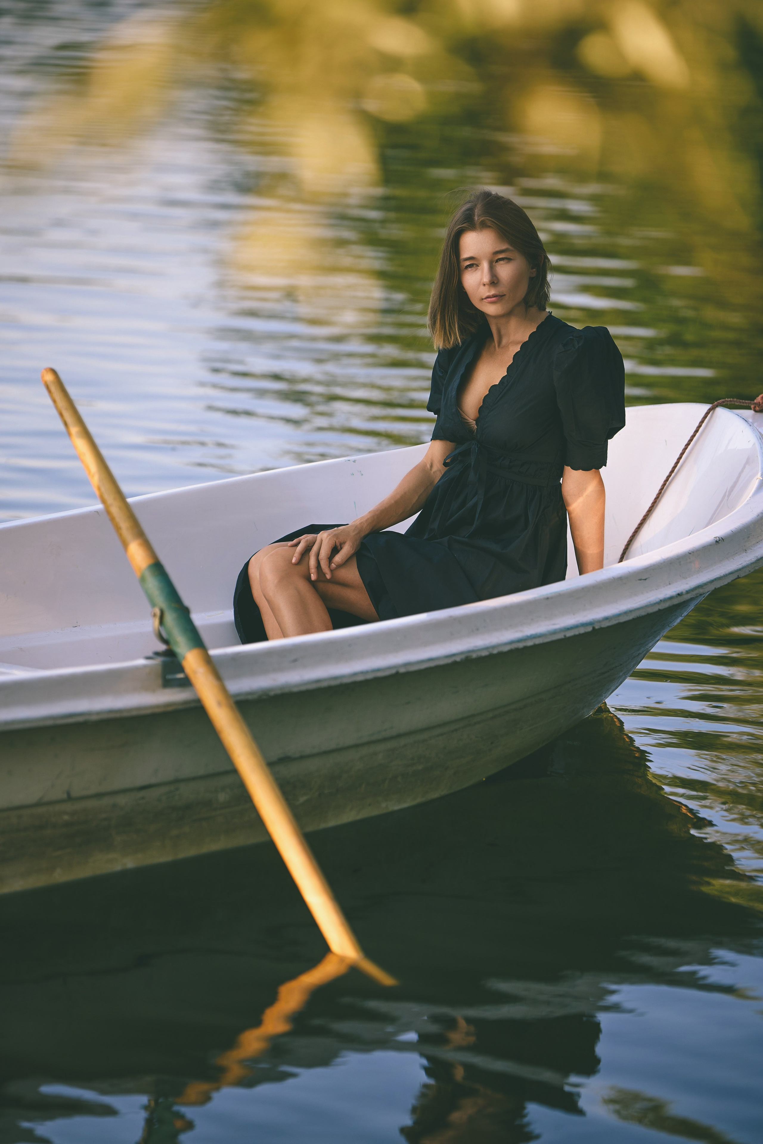 Уличная фотосесия девушка в черном платье в лодке