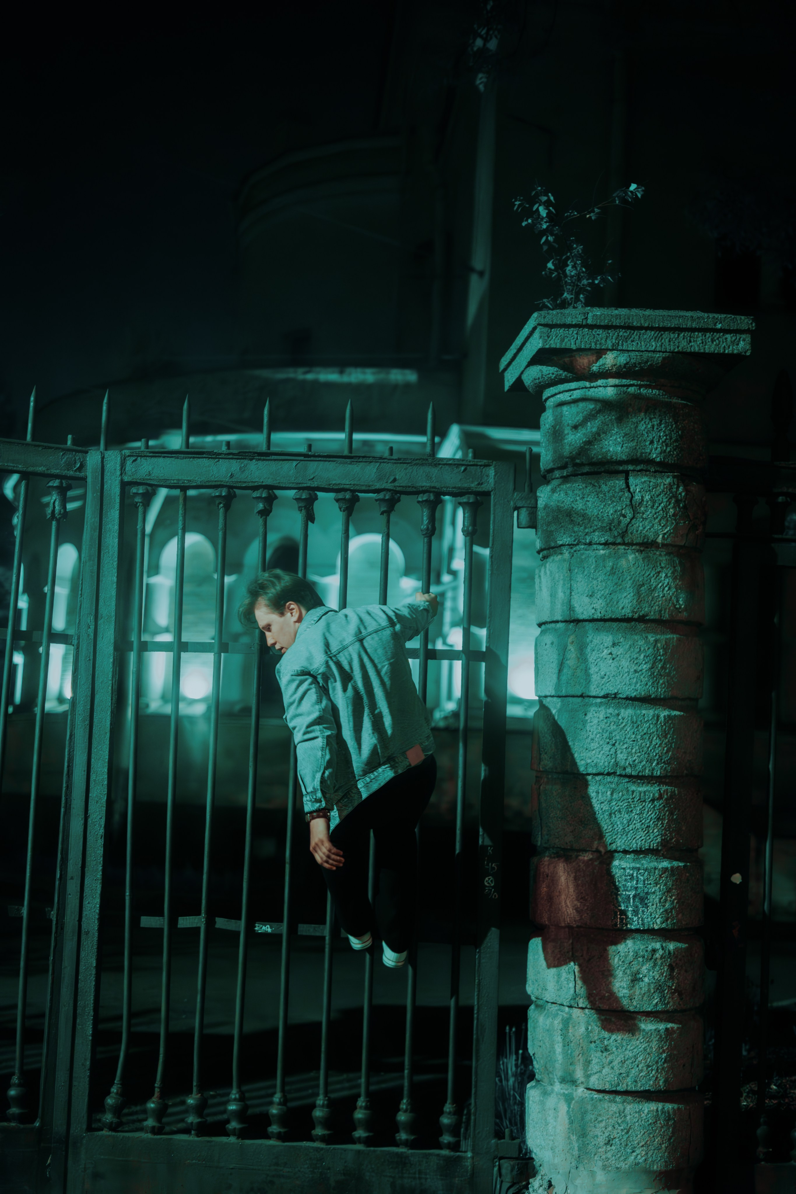 молодой человек спрыгивает с забора ночью