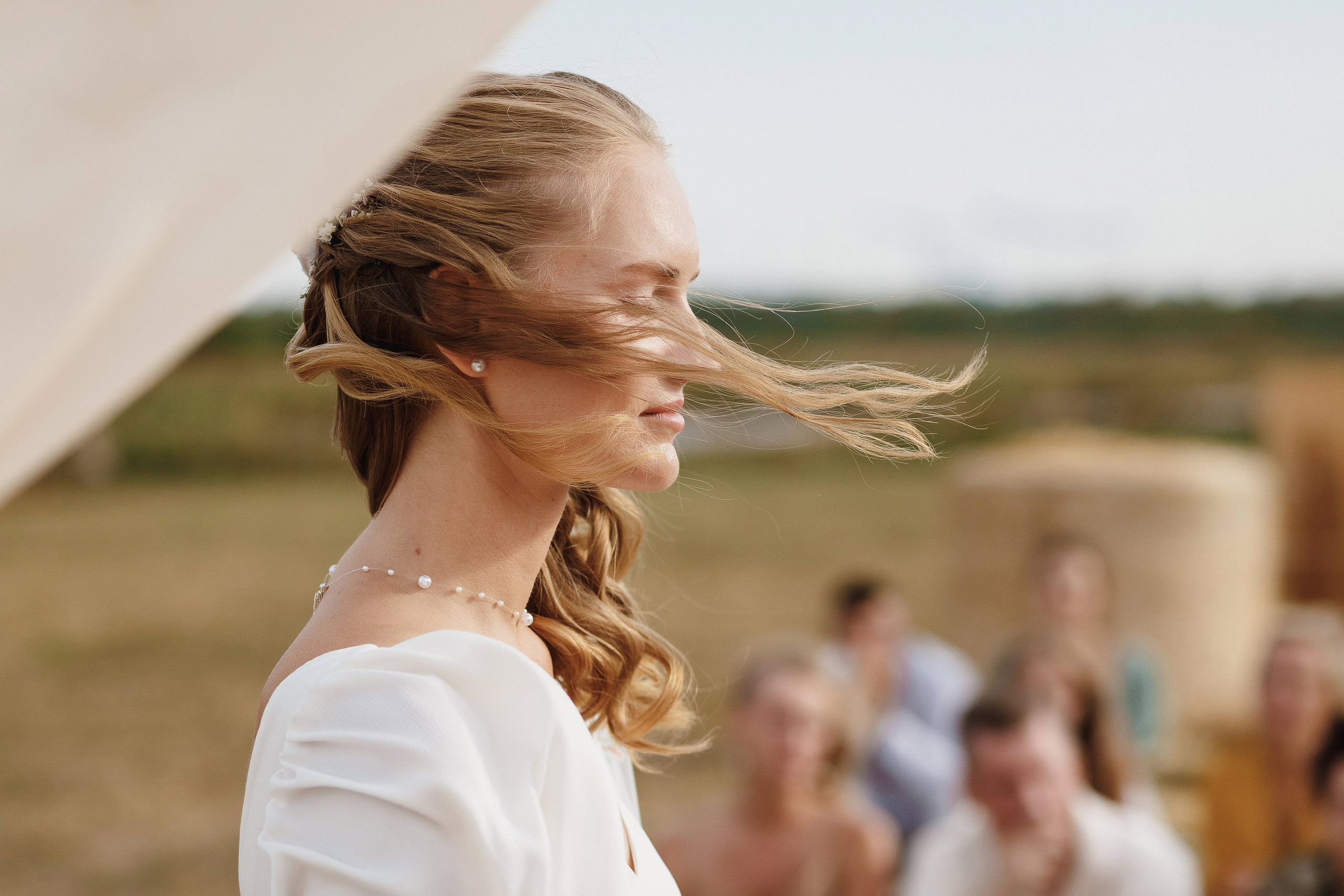 Портрет невесты Полины с развевающимися волосами на фоне гостей — свадебный фотограф Таганрог