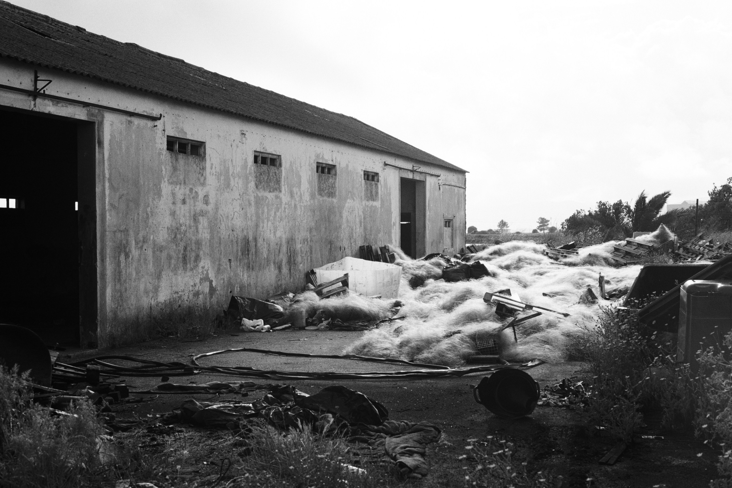 Старые рыболовные сети на рядом с ангаром, черно-белый пейзаж. Сетубал, Португалия