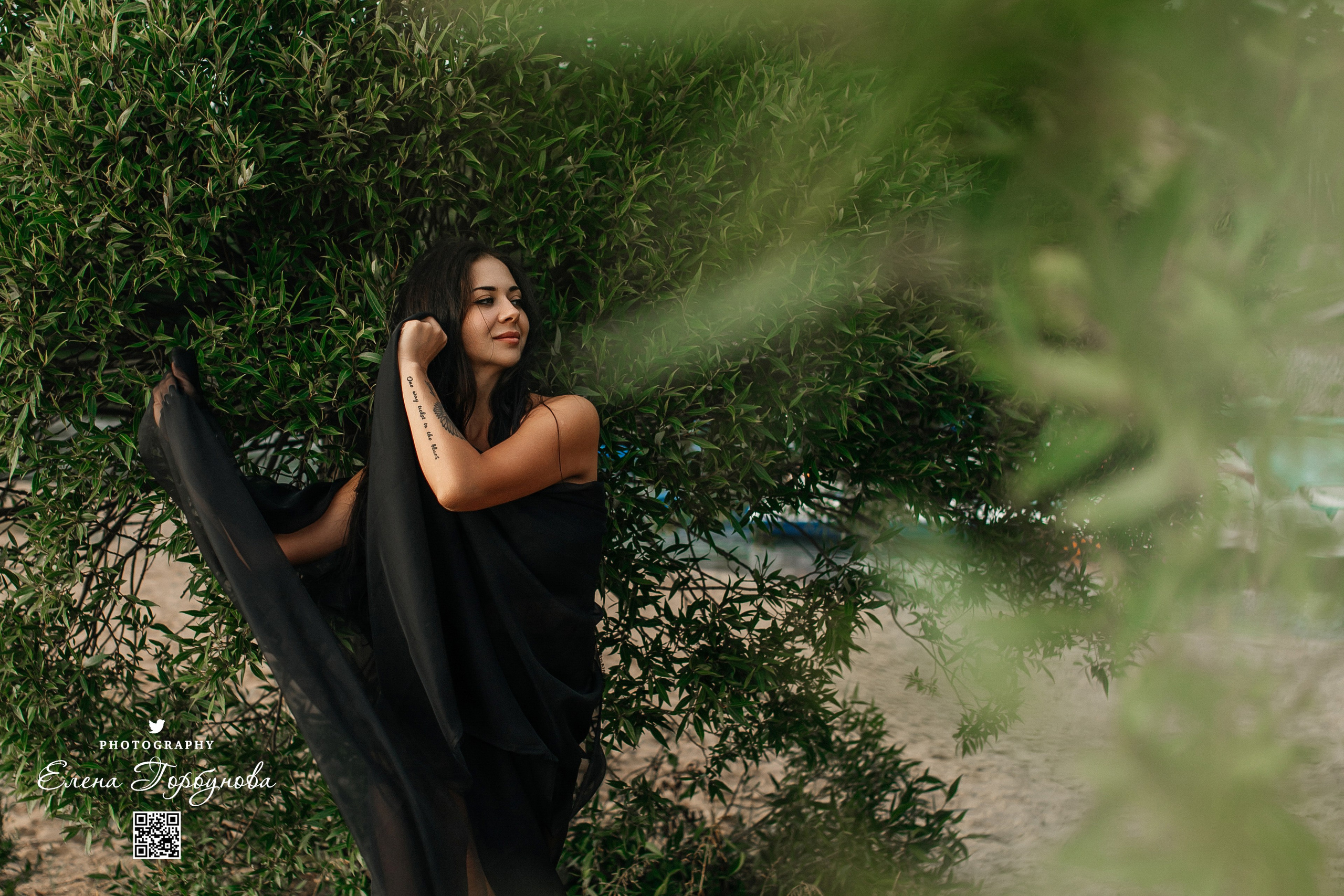 Фотосессия с черной тканью. Легкая черная вуаль летит на вертру. Фотосессия у реки черная серия с тканью. Девушка укуталась в черную ткань. Прогулка по набережной. Песок, речка, модель в черном. Качели над водой, Закат. Девушка лежит на песке. В зеленых деревьях