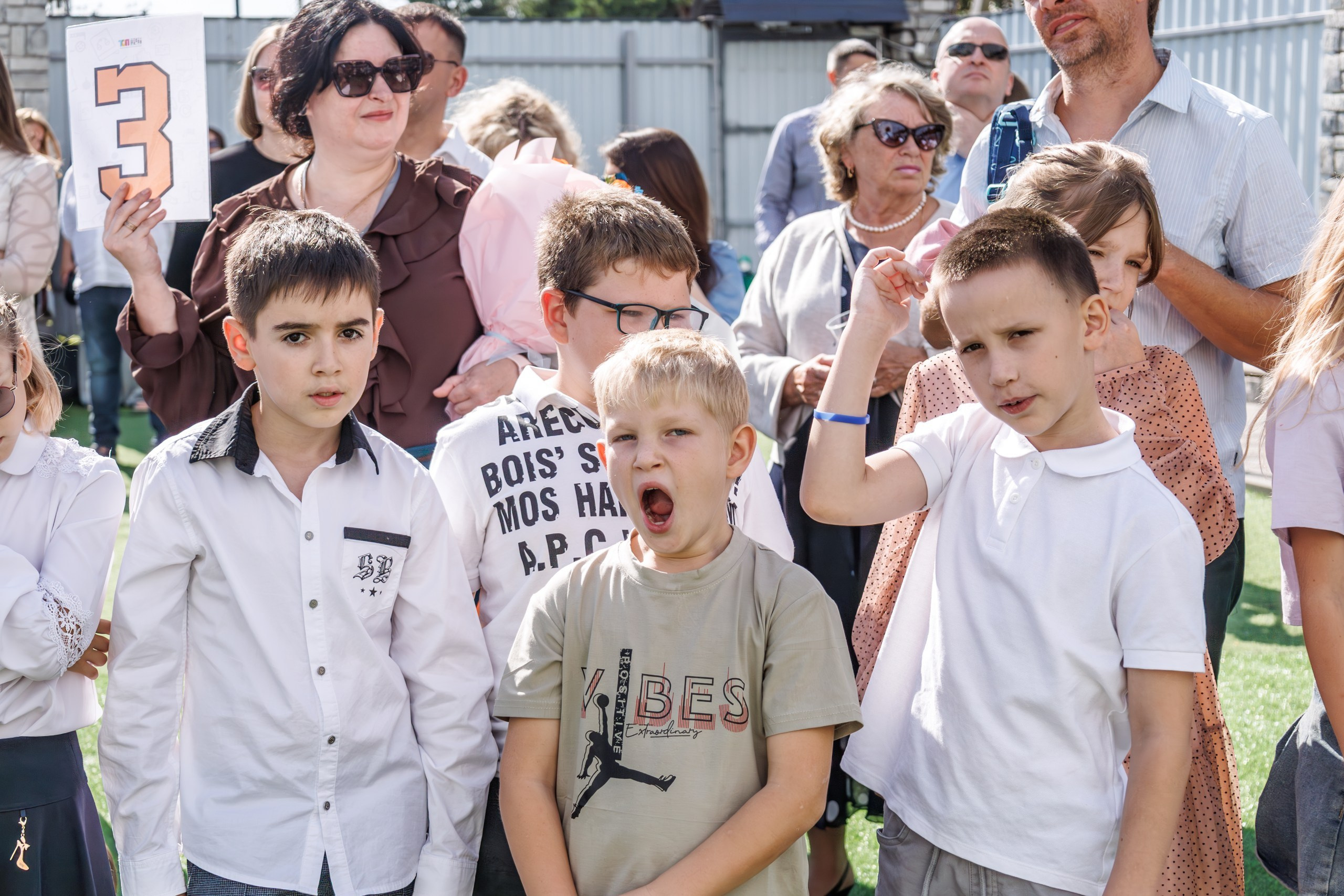 Линейка 1 сентября в школе - дети с букетами, радостные родители и учителя; дети обнимаются, радуются встрече с друзьями после каникул