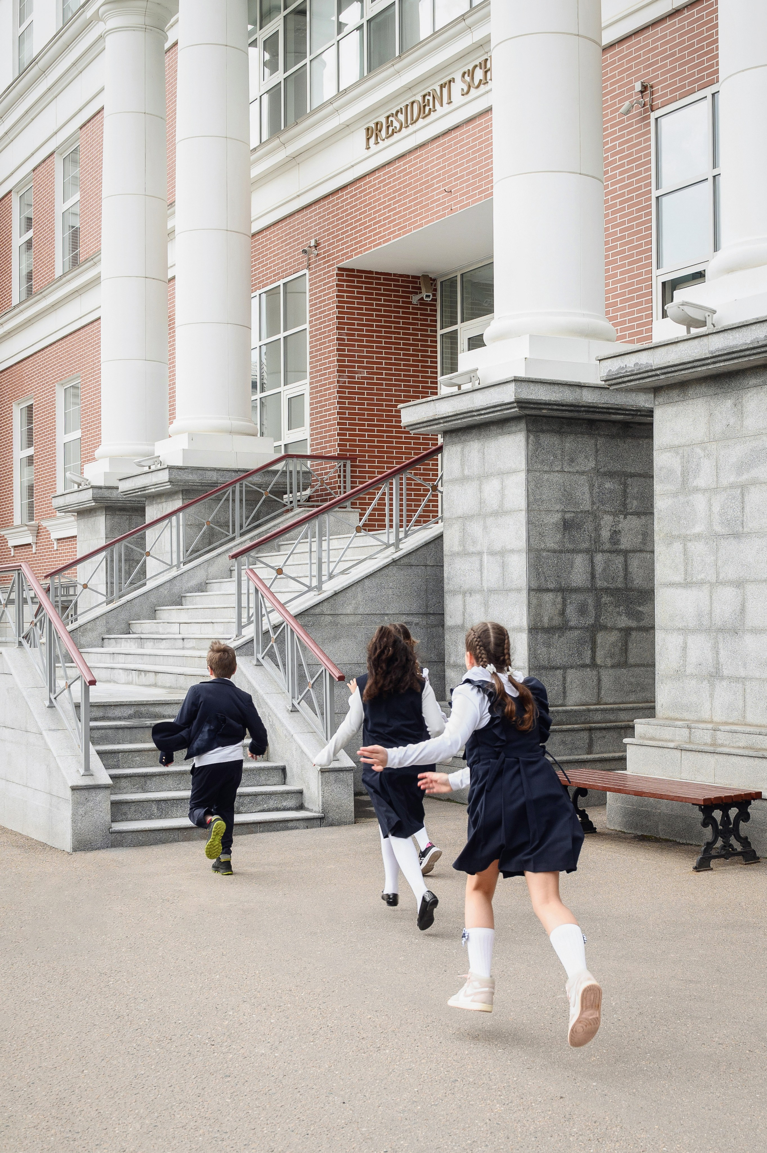 Школьники бегут по территории у фасада школьного здания