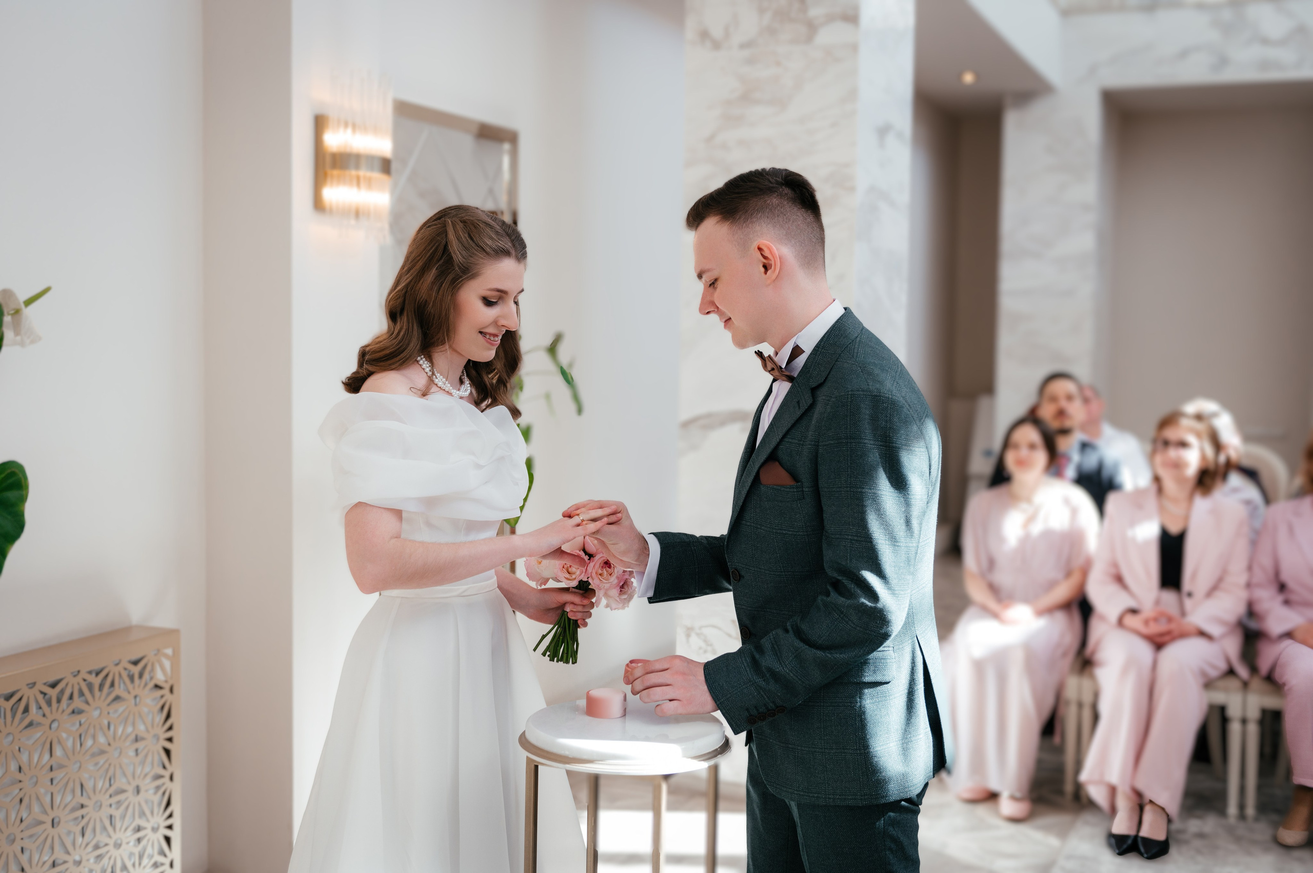 Молодожены обмениваются кольцами в загсе.