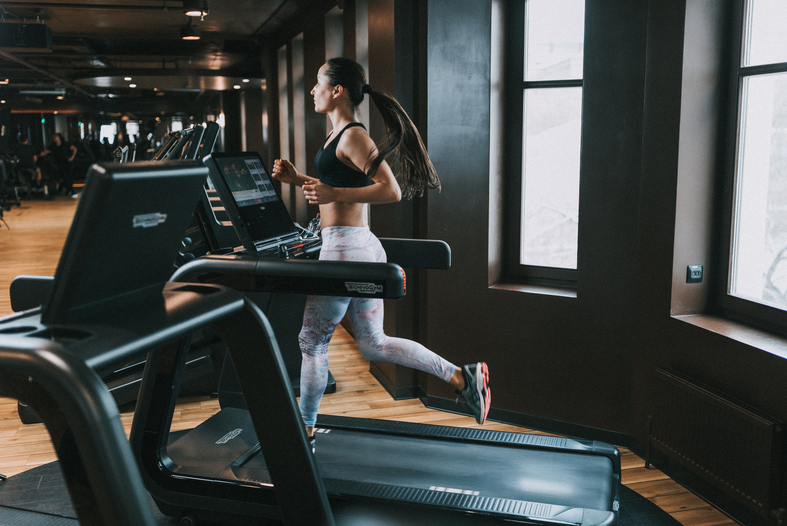 девушка в фитнес клубе бежит на беговой дорожке