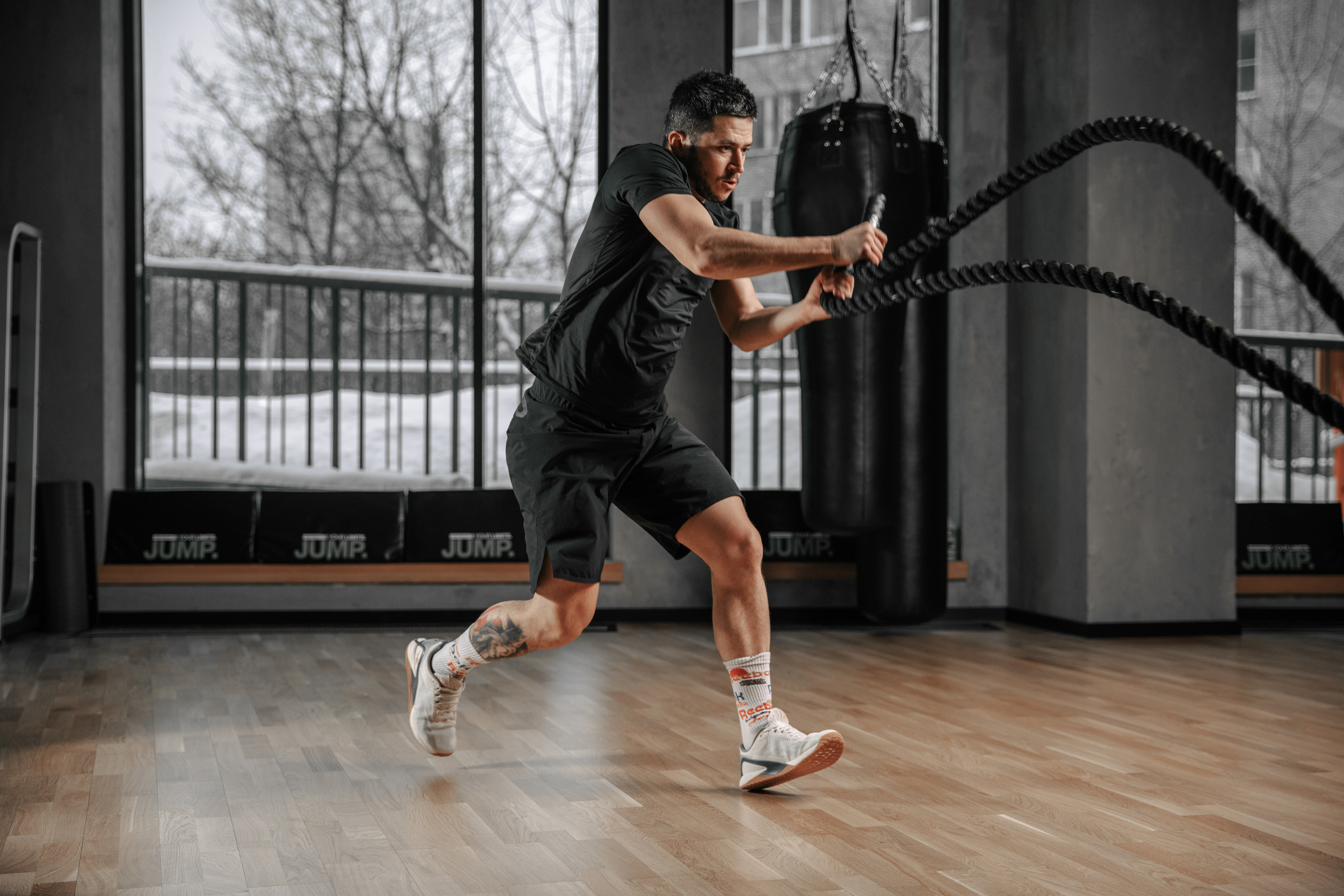 мужчина тренер выполняет упражнения с канатами в фитнес клубе