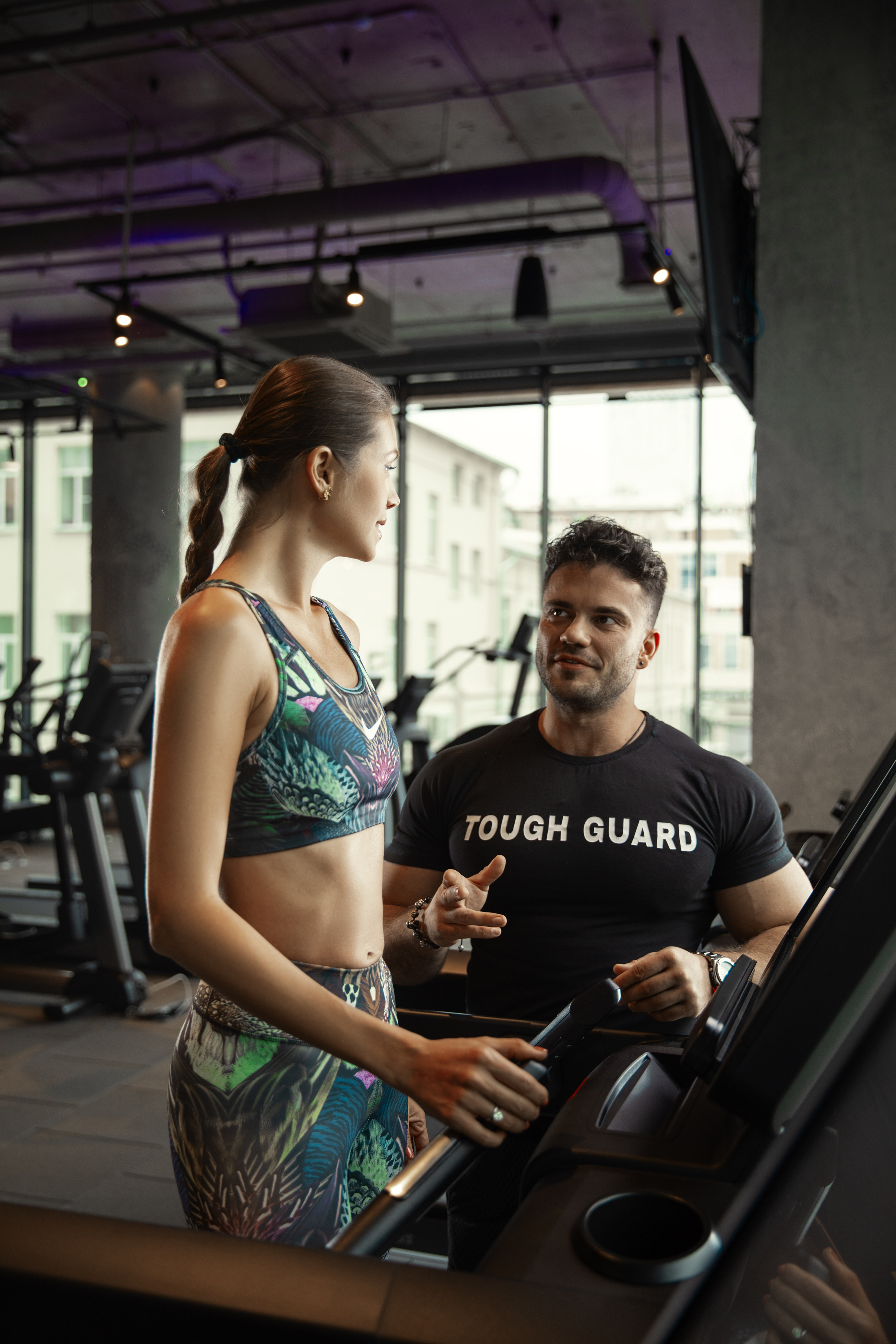 тренер мужчина общается с клиентом на беговой дорожке 