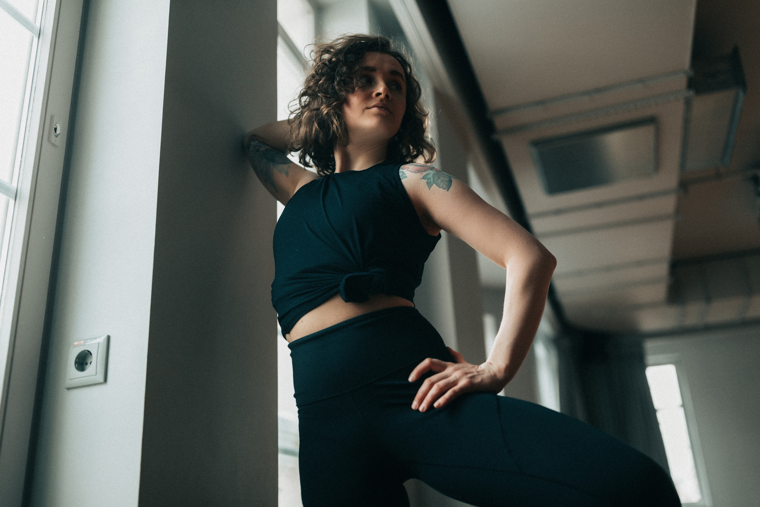 девушка танцора стоит облокотившись на стену и смотрит в сторону