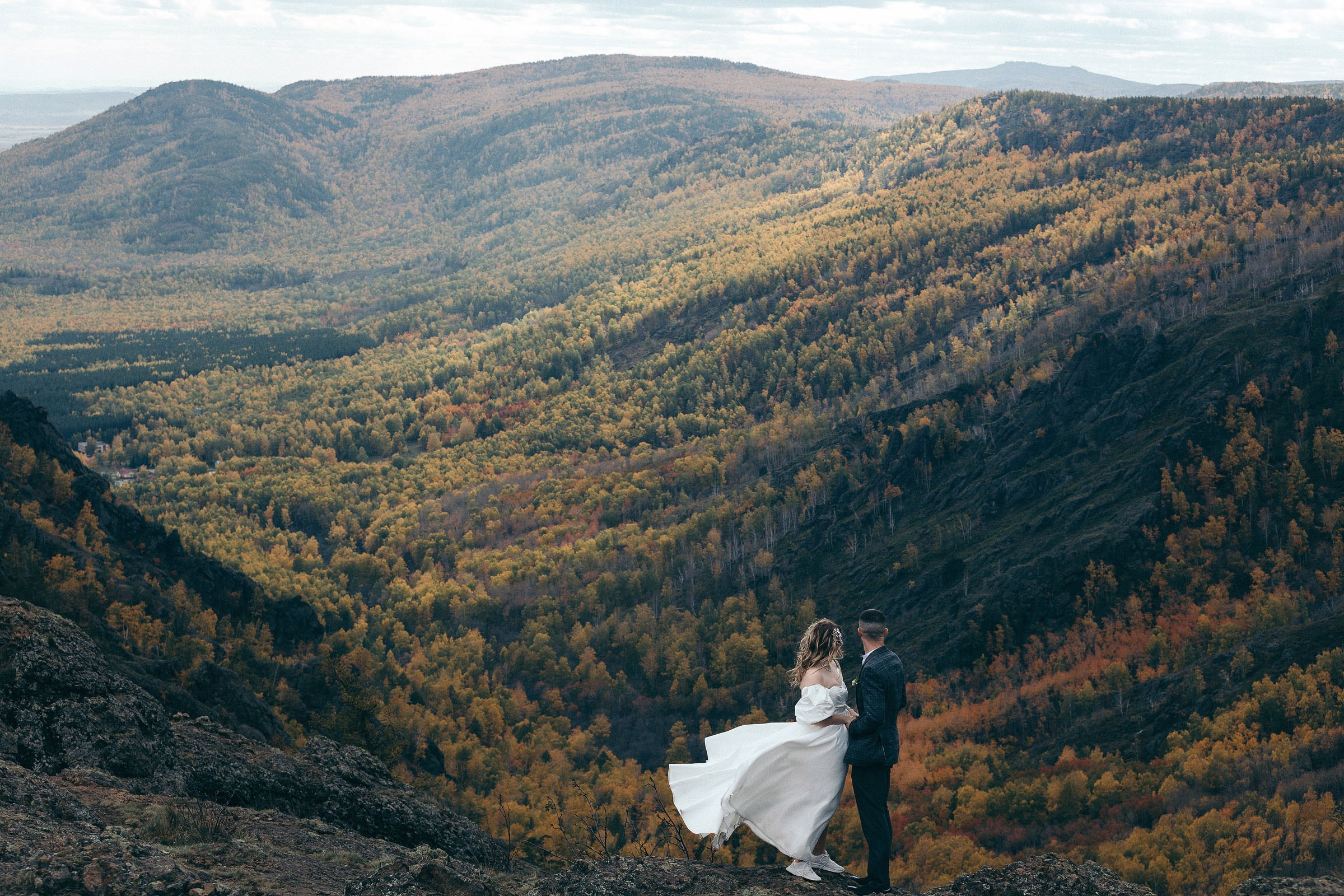 Свадебная пара позирует на фоне горного ущелья на озере Банное 