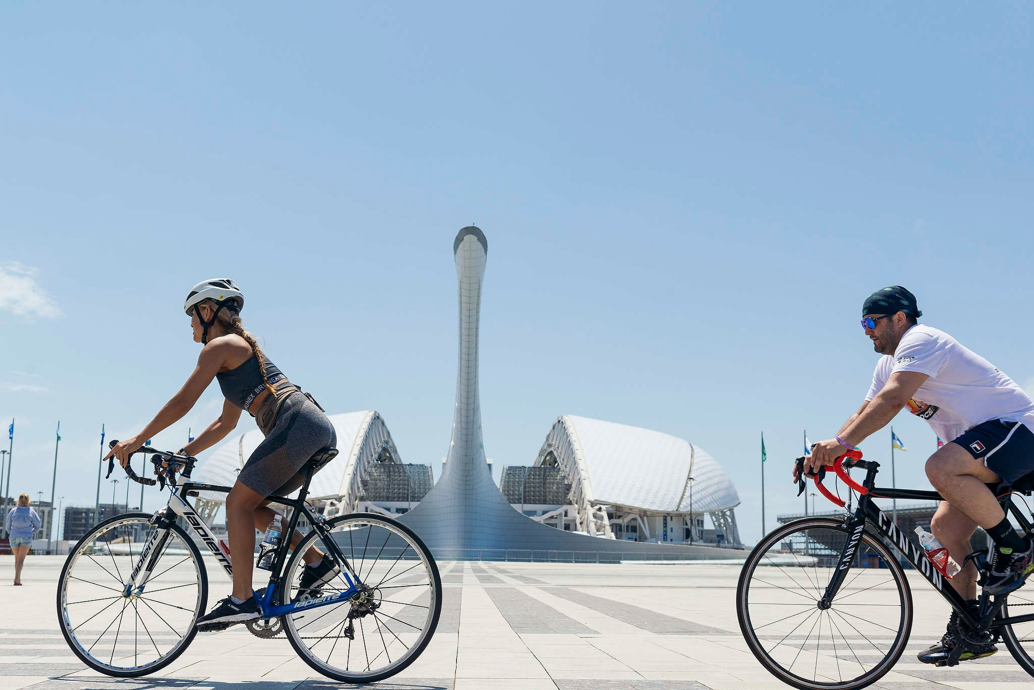 Любительская хоккейная команда катается на велосипедах на фоне стадиона Фишт в Олимпийском парке на сборах в городе Сочи. Съемка 2023 года. 