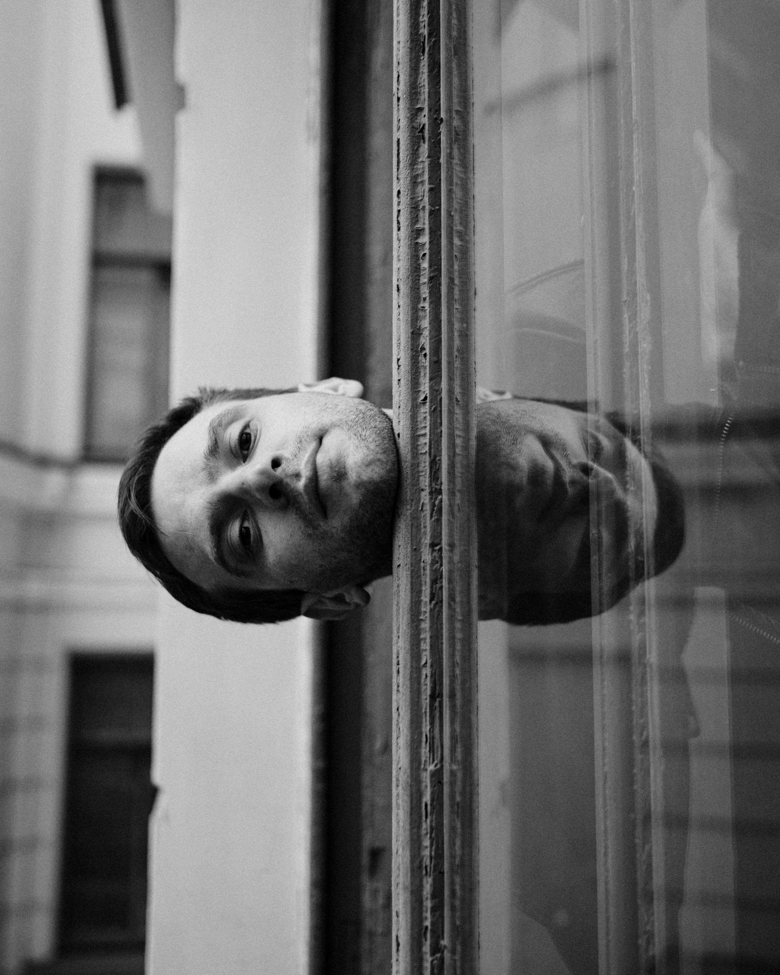 Парень выглядывает из окна и смотрит в камеру