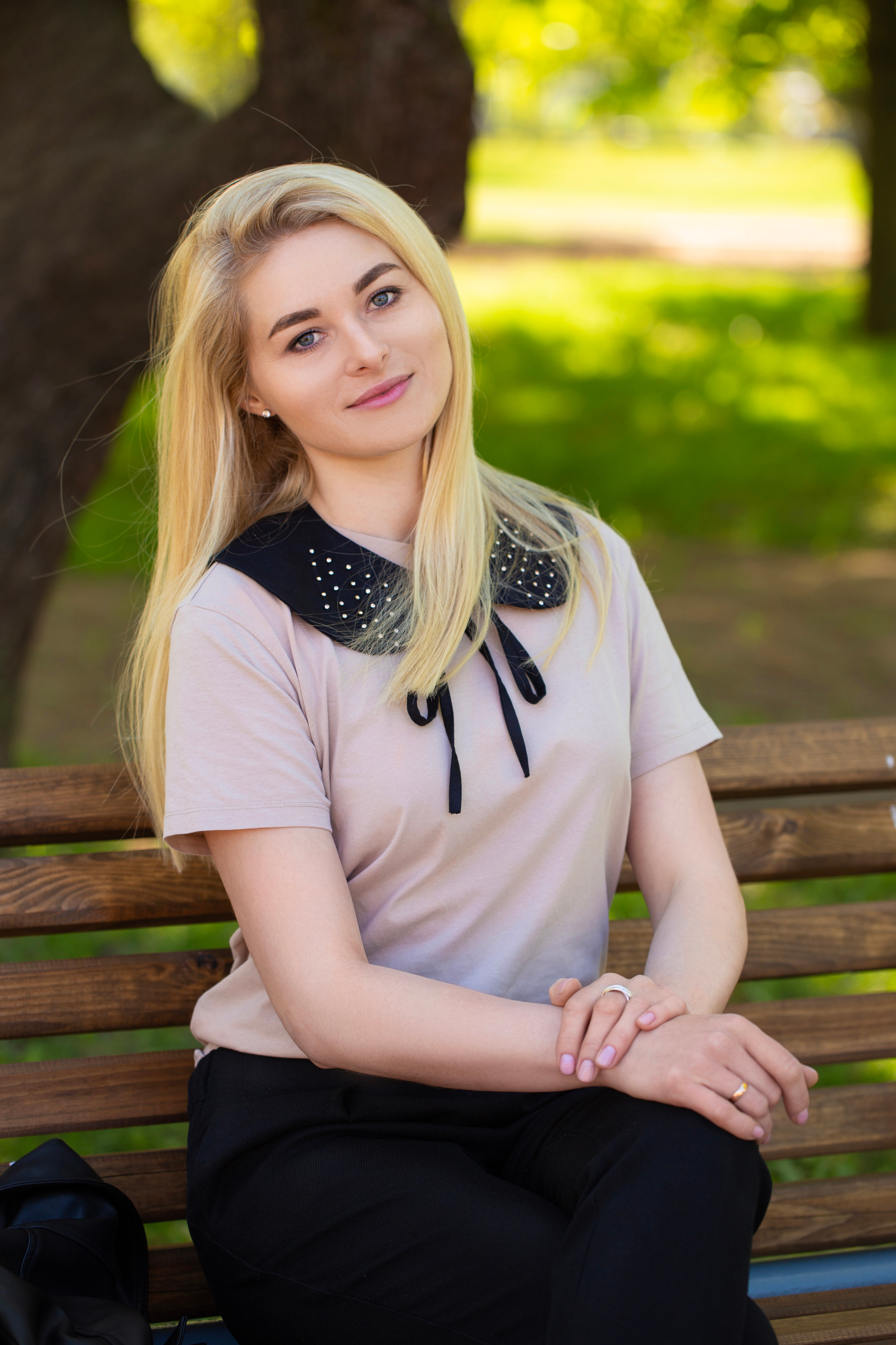 молодая блондинка сидит в парке на скамейке