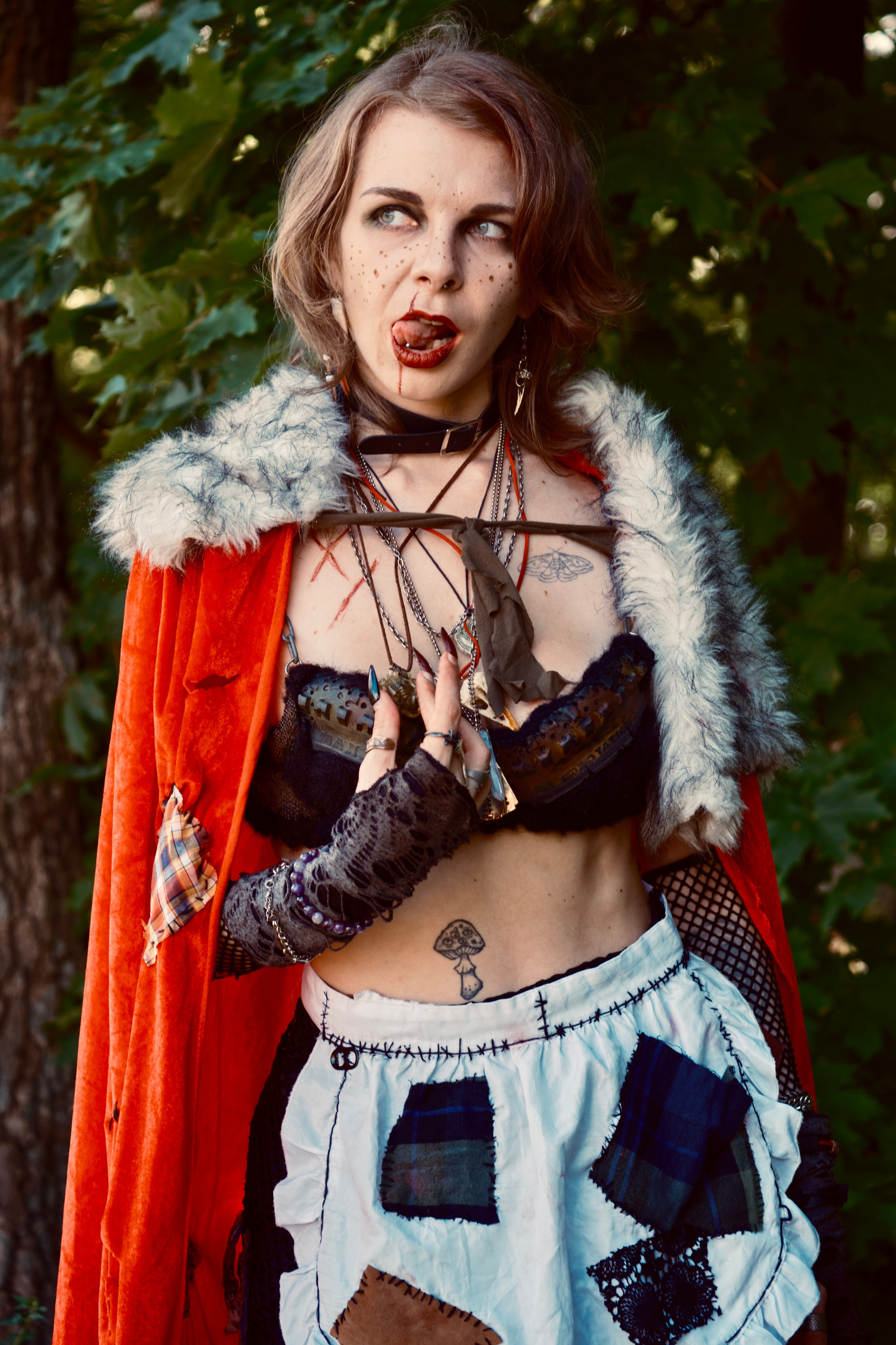 Девушка в красном плаще с корзиночкой гуляет в лесу и показывает язык