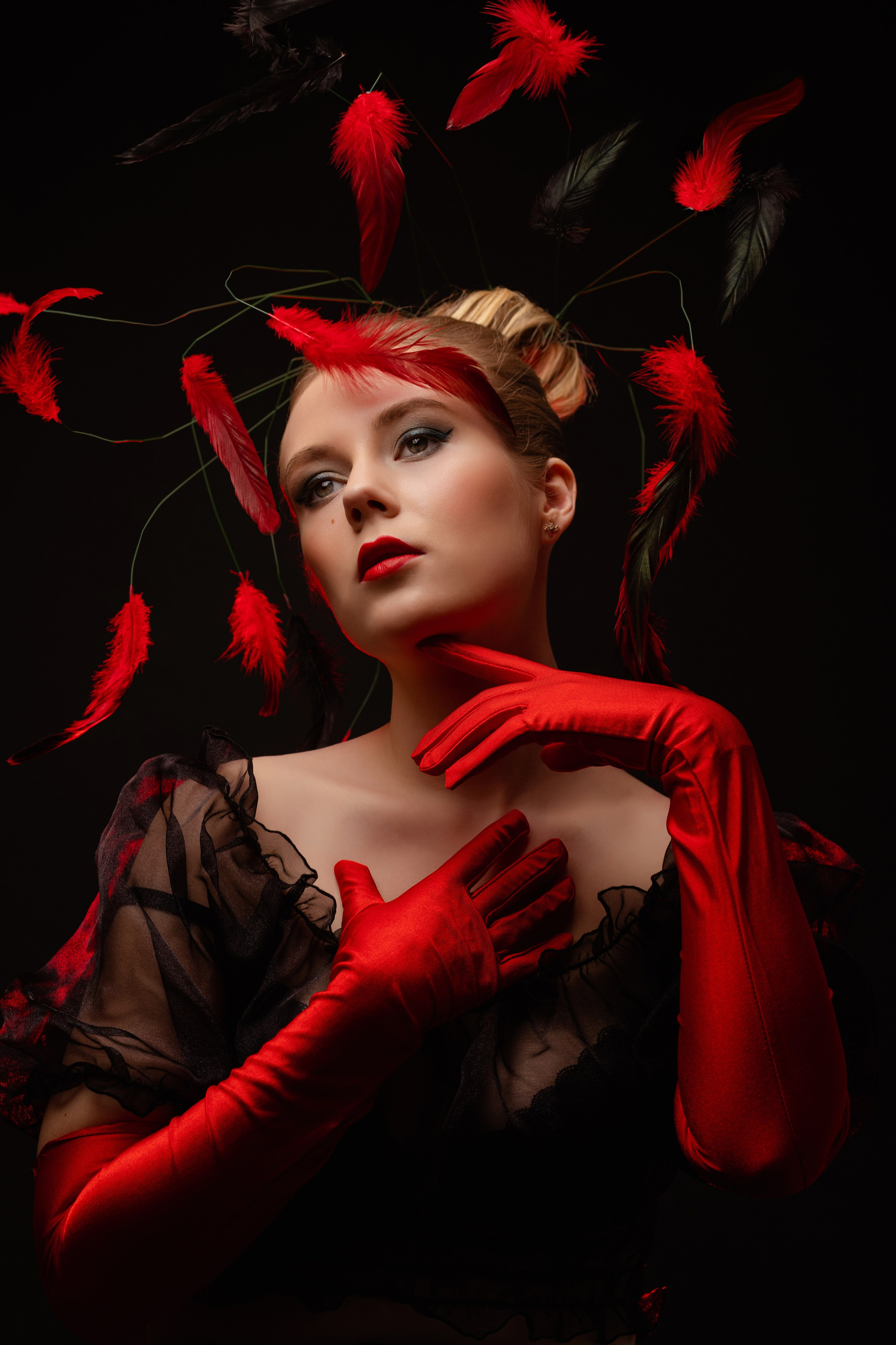 Девушка в красных перчатках среди красных перьев