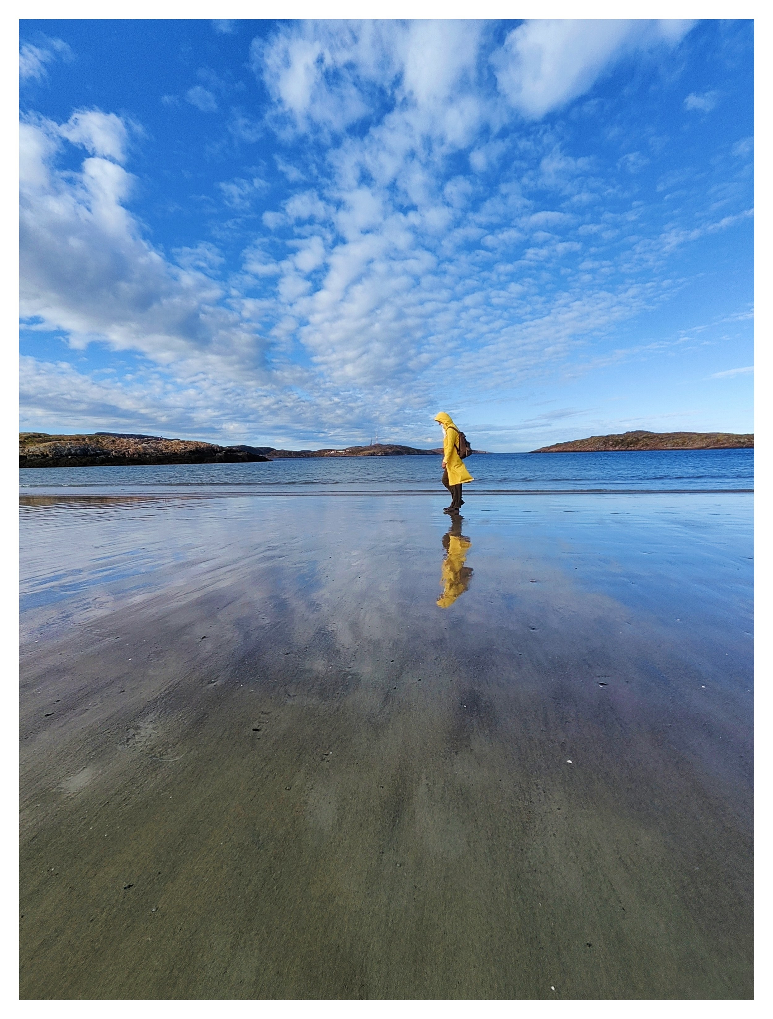 человек в желтой куртке идет в Териберке по берегу вво время отлива