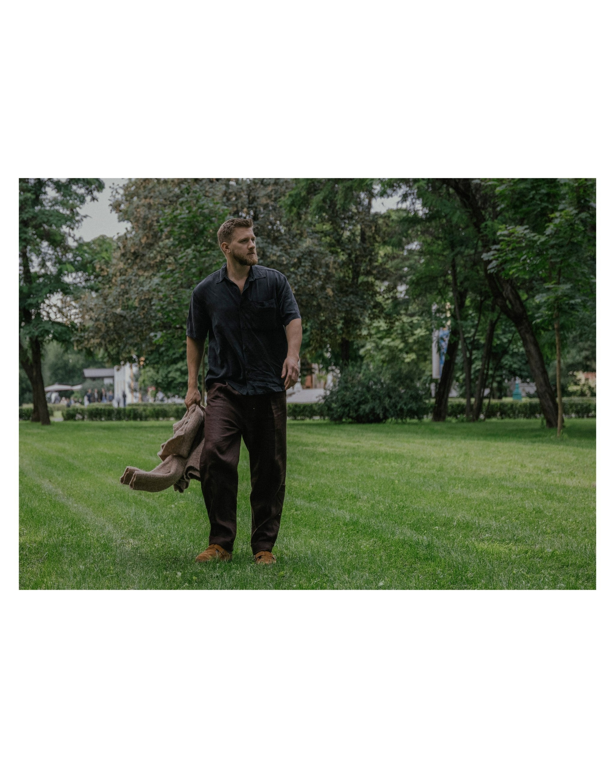 мужчина в льняной рубашке и брюках идет по полю