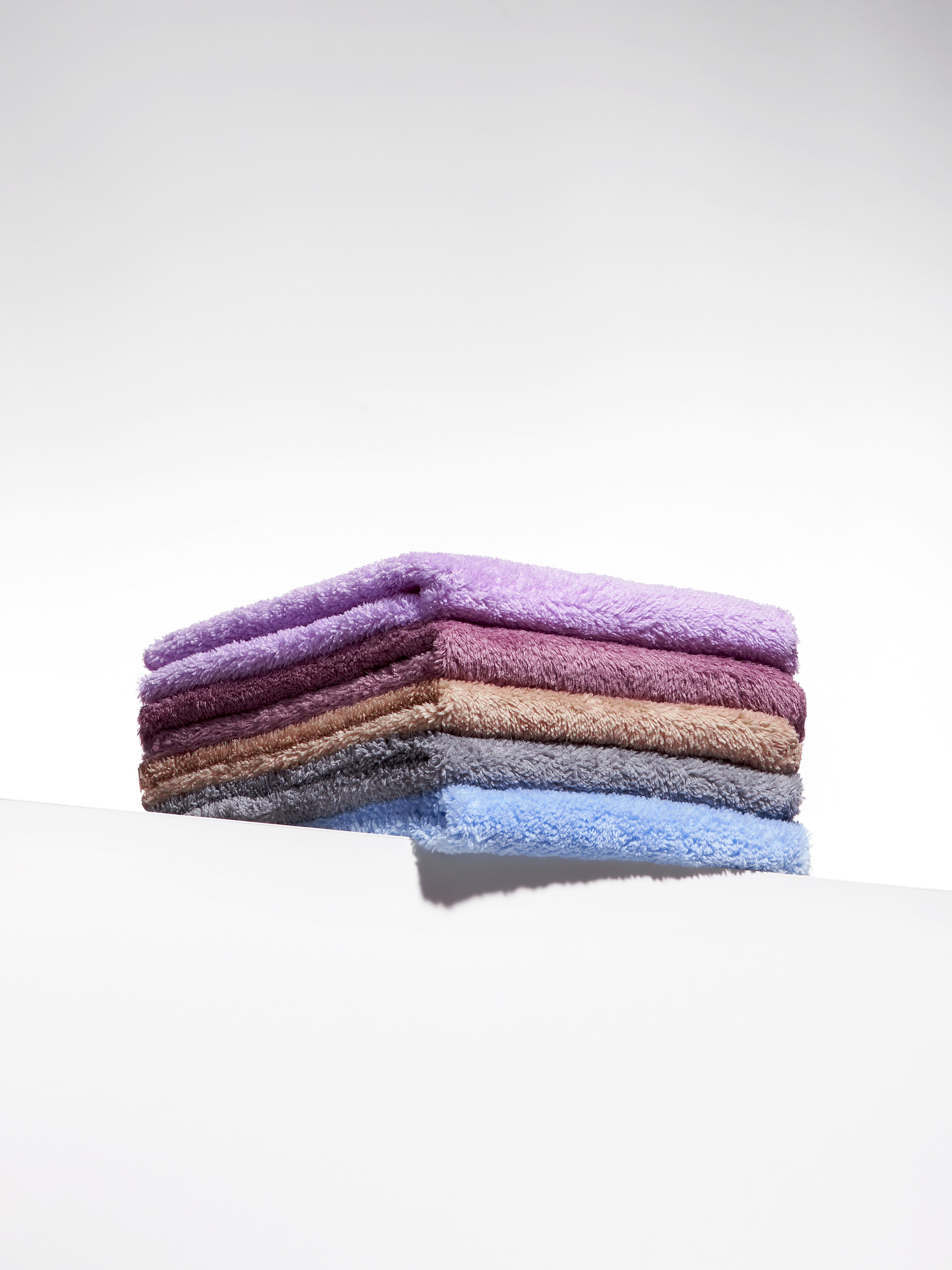 Предметная рекламная фотосъёмка цветных салфеток для уборки на подиуме на белом фоне