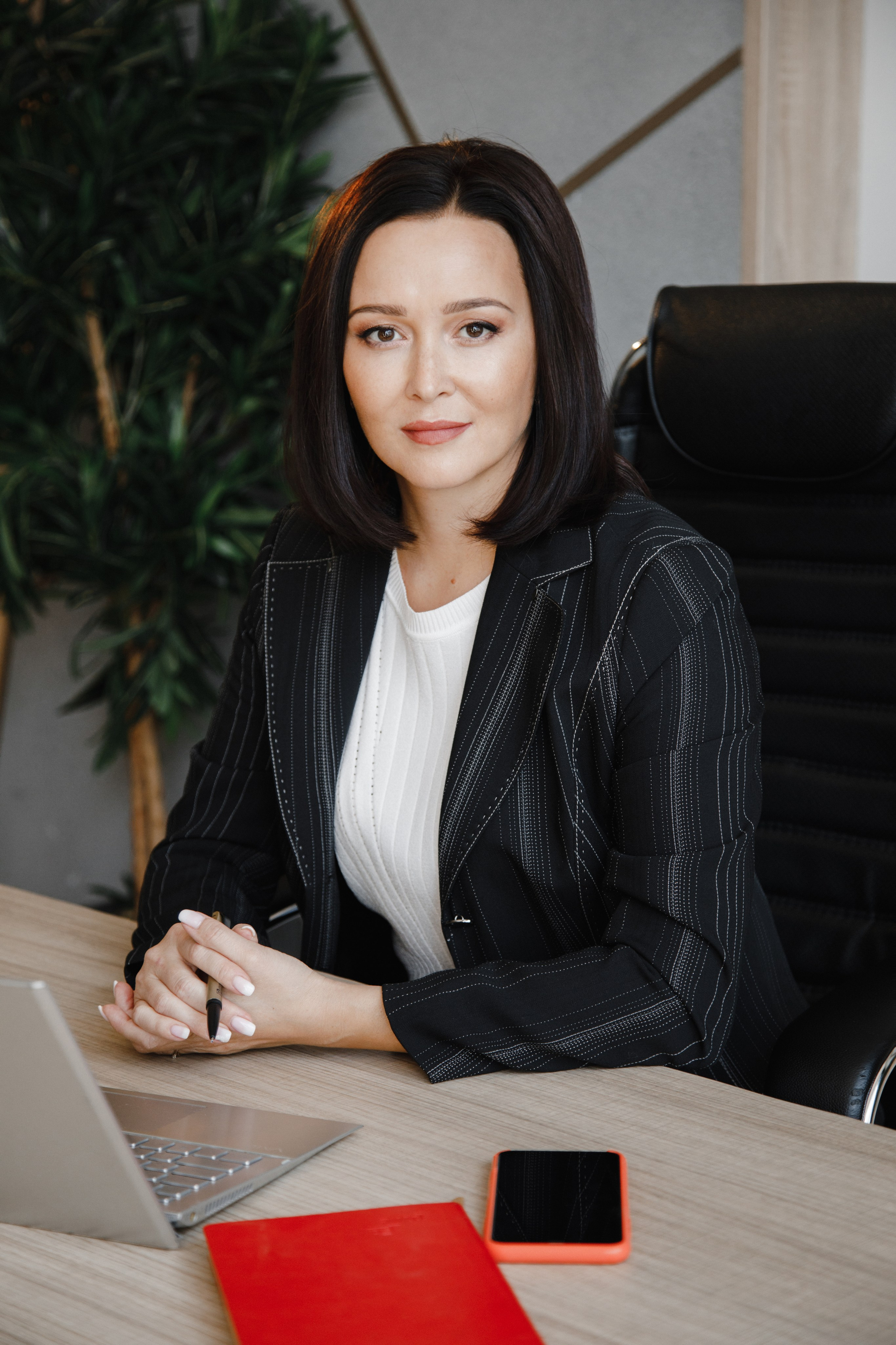 Девушка-юрист в строгом костюме работает за своим рабочим столом.