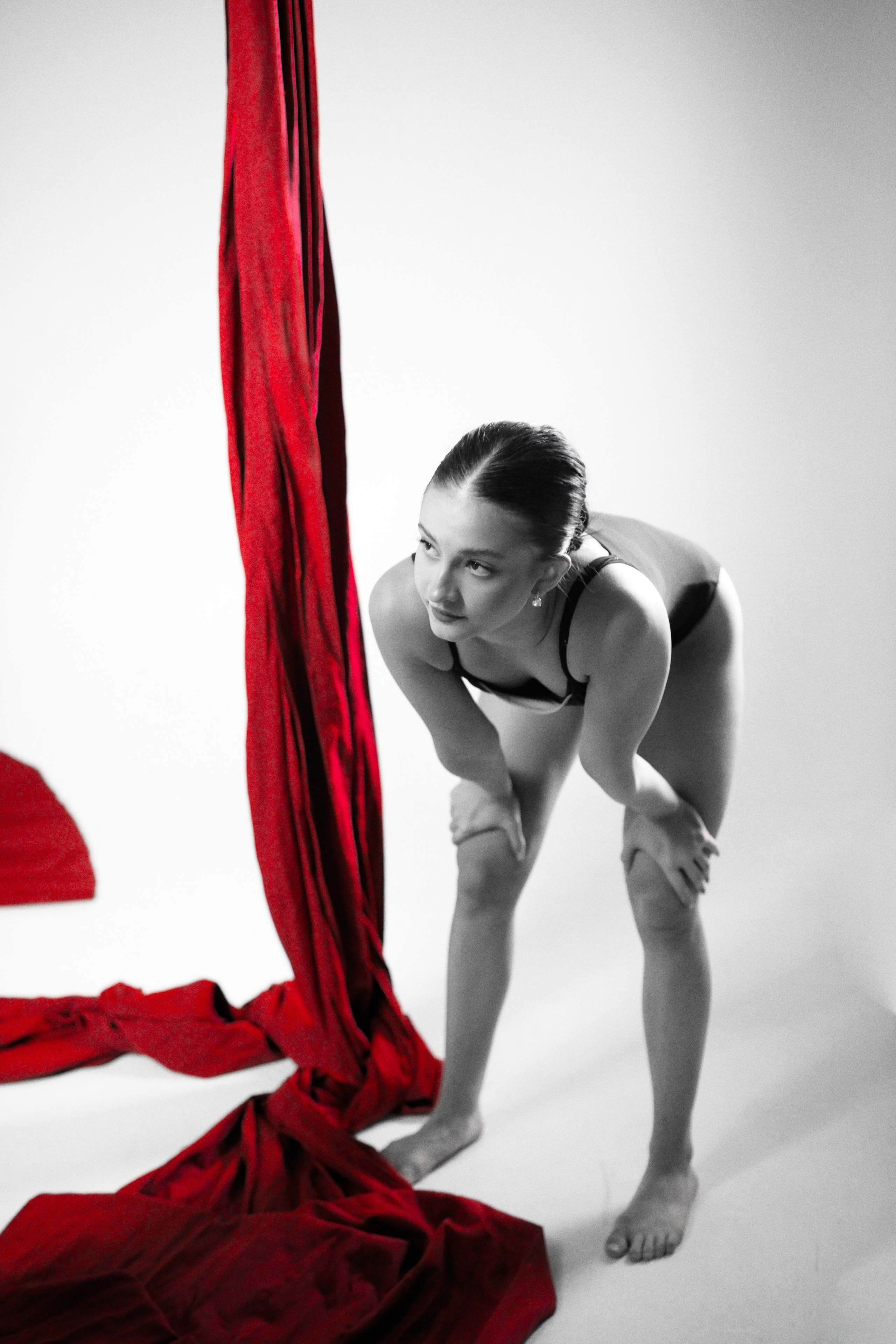 Закулисье фотосессии: воздушная гимнастка у красных полотен в студии, естественный момент подготовки к кадру