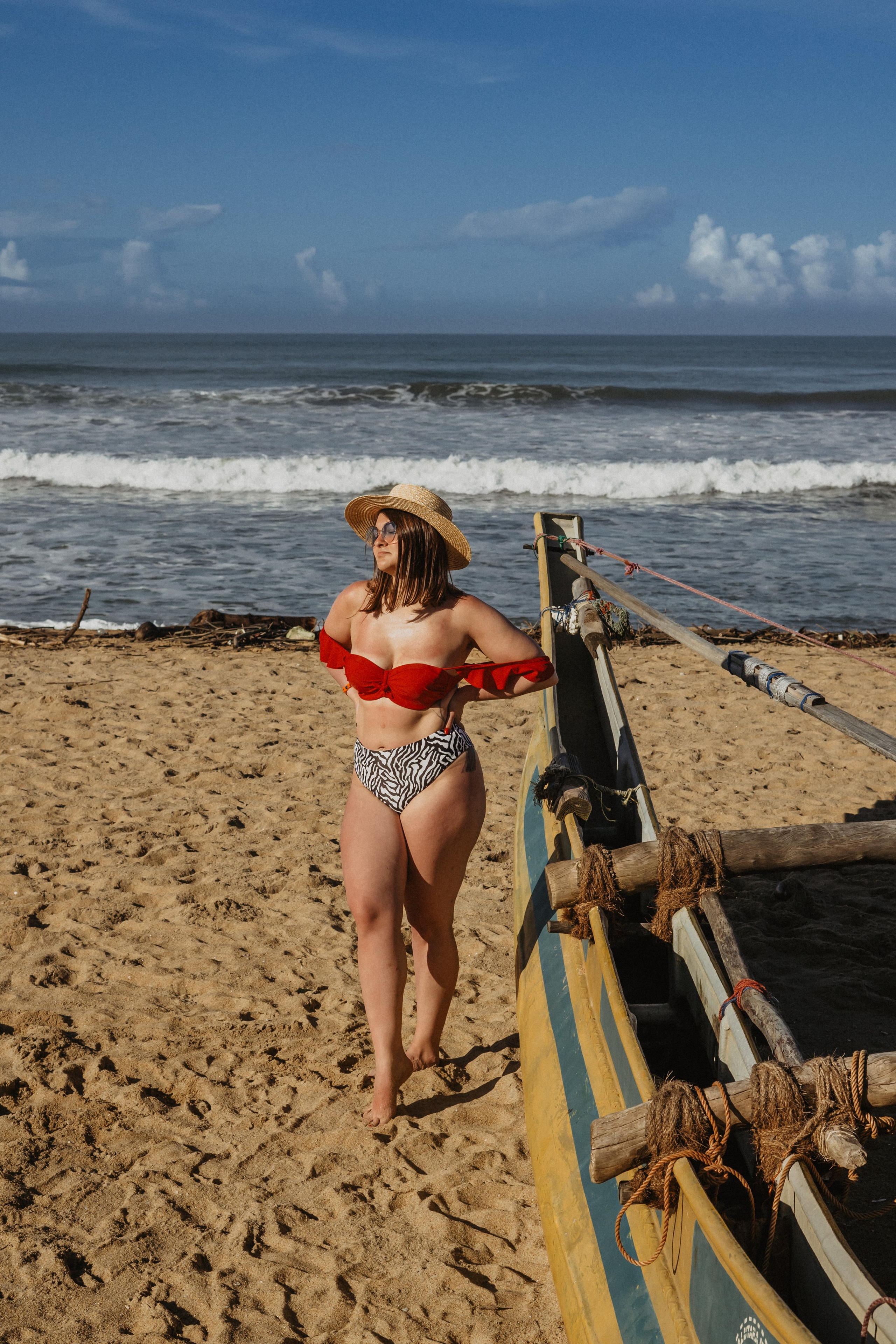 a girl in a straw hat with the sea and beach in the background