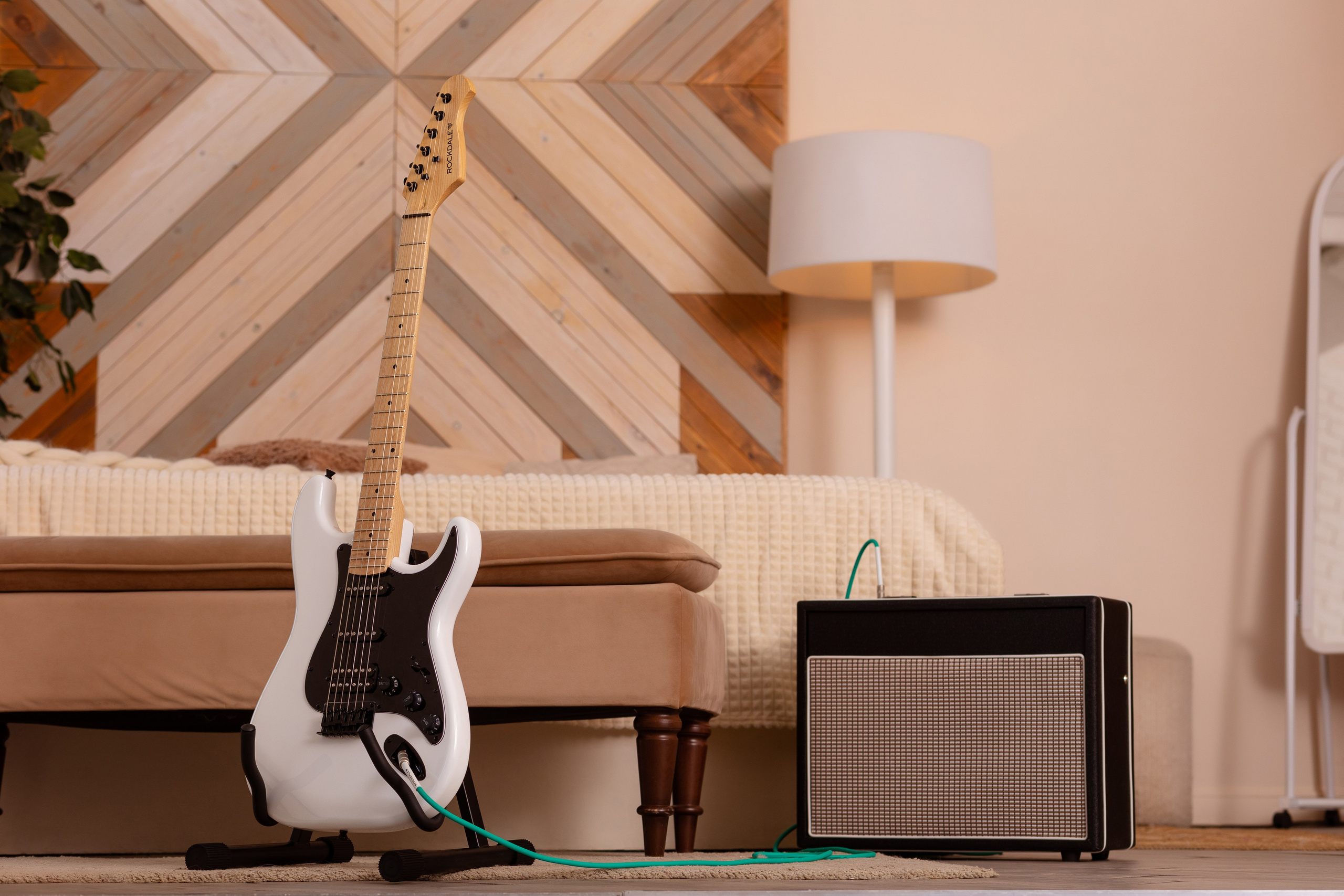 На подставке стоит бело-черная акустическая гитара.