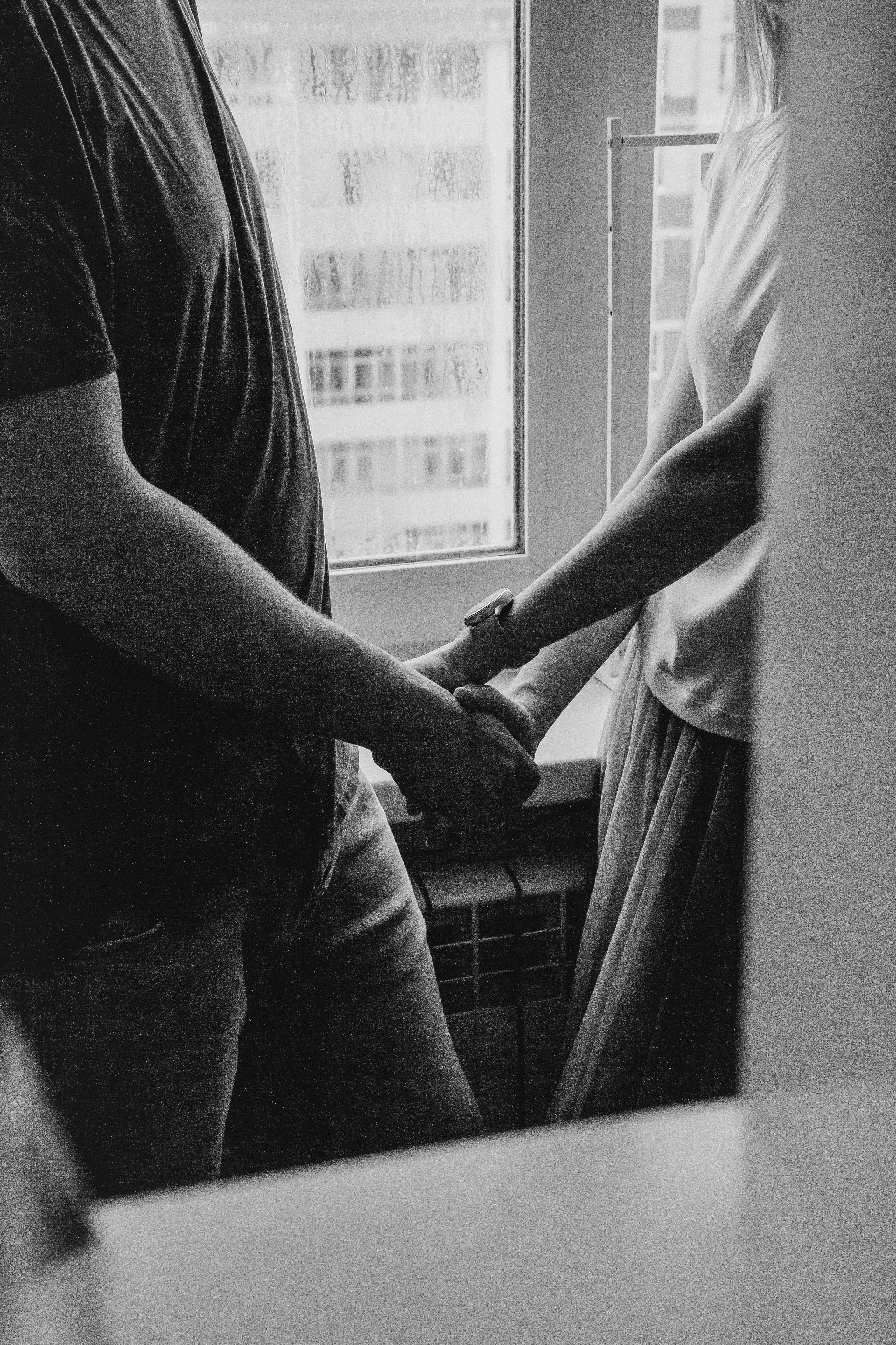 Муж и жена держатся за руки на фоне окна