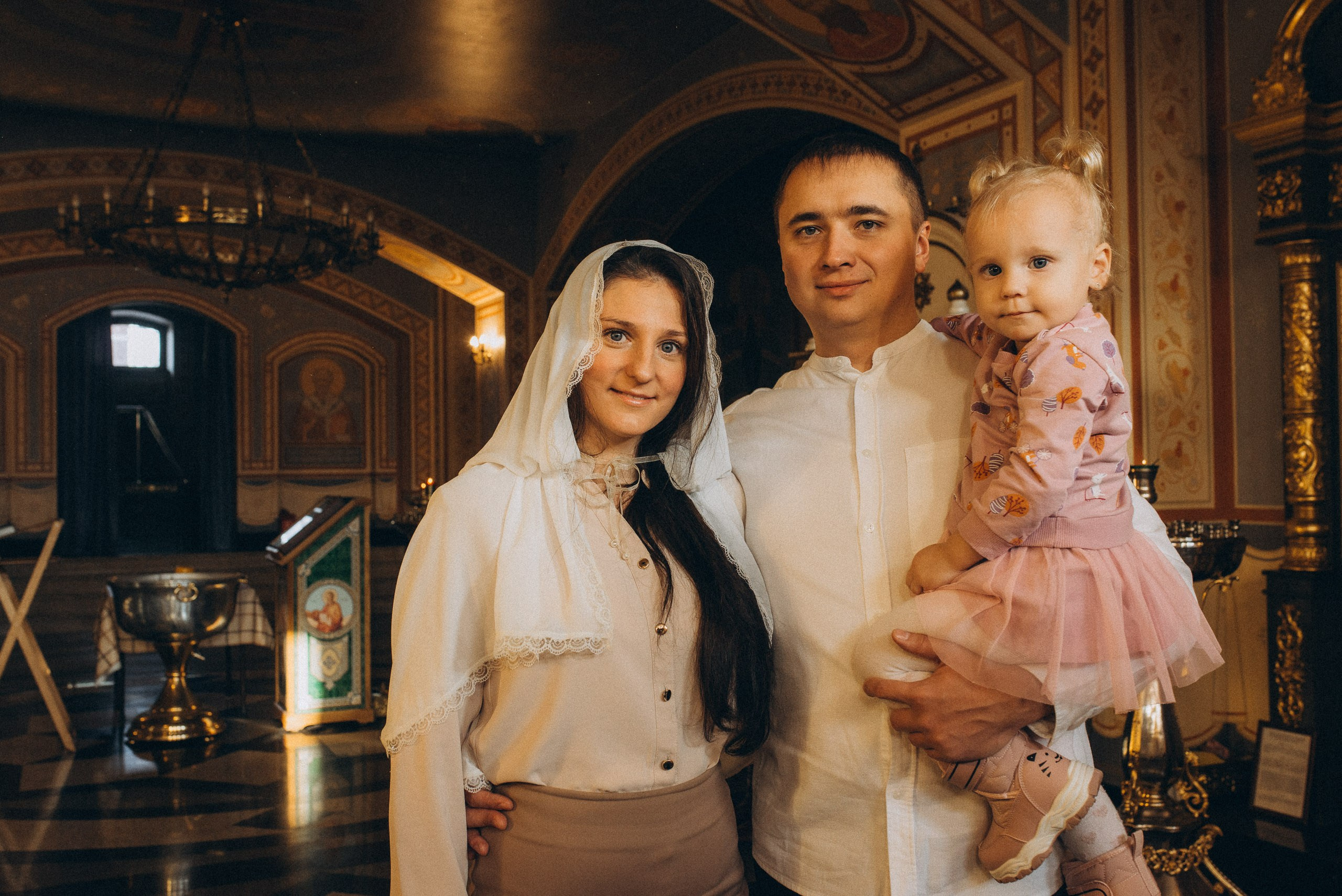 Семейная фотосессия в церкви — крестный со своей женой и дочерью в интерьере храма Новосибирске