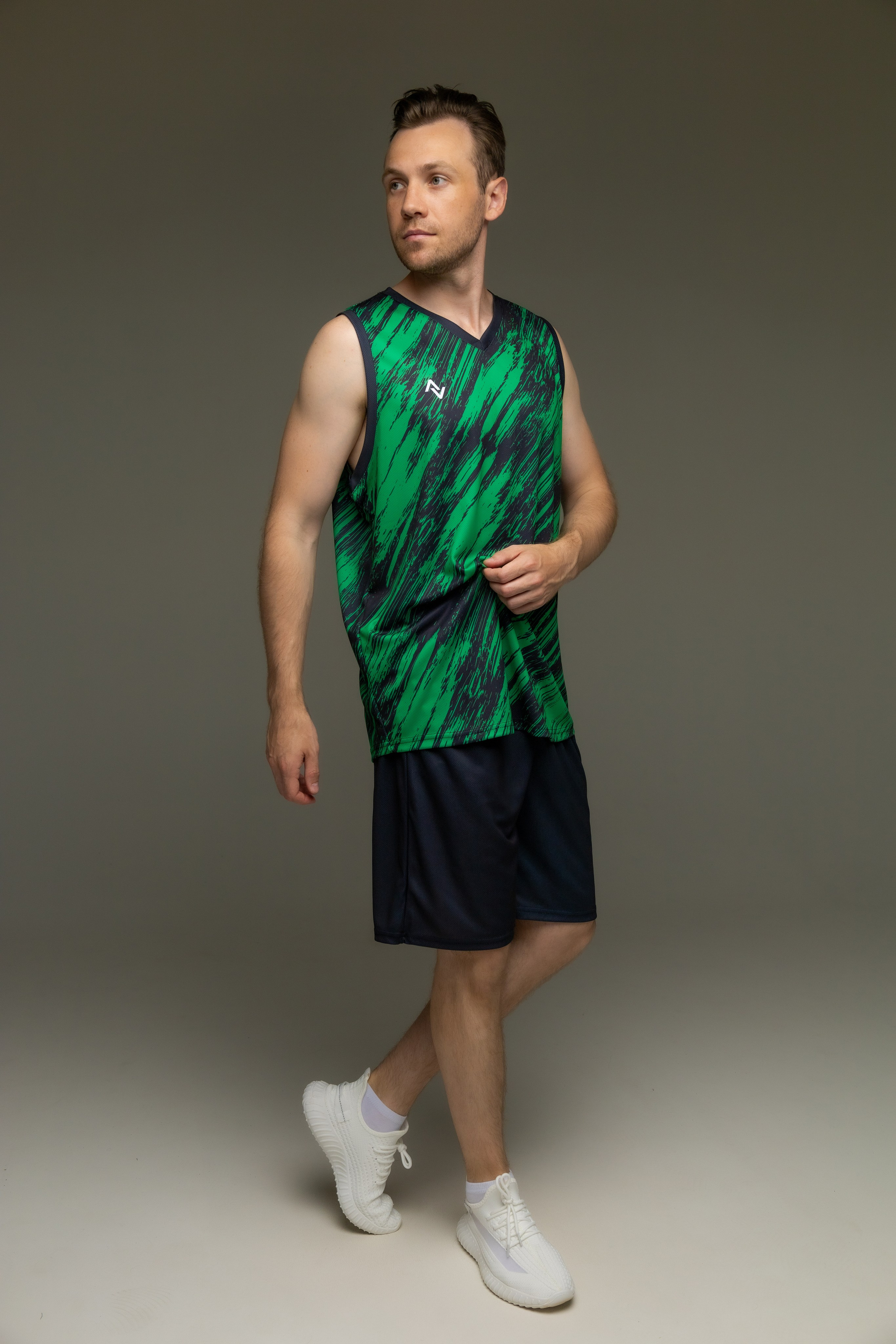 Парень в зеленой спортивной майке и черных шортах