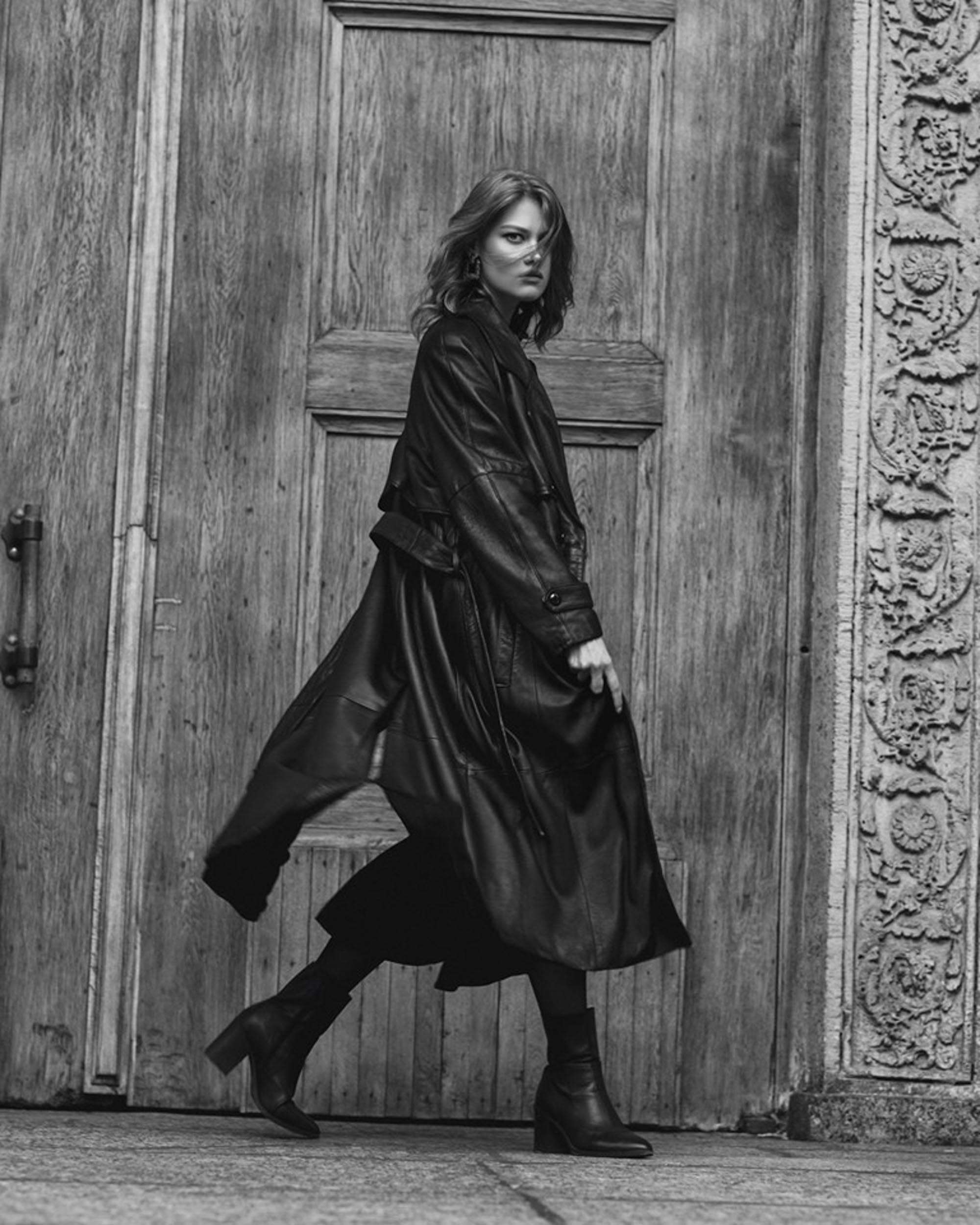 Девушка в кожаном плаще на фоне двери