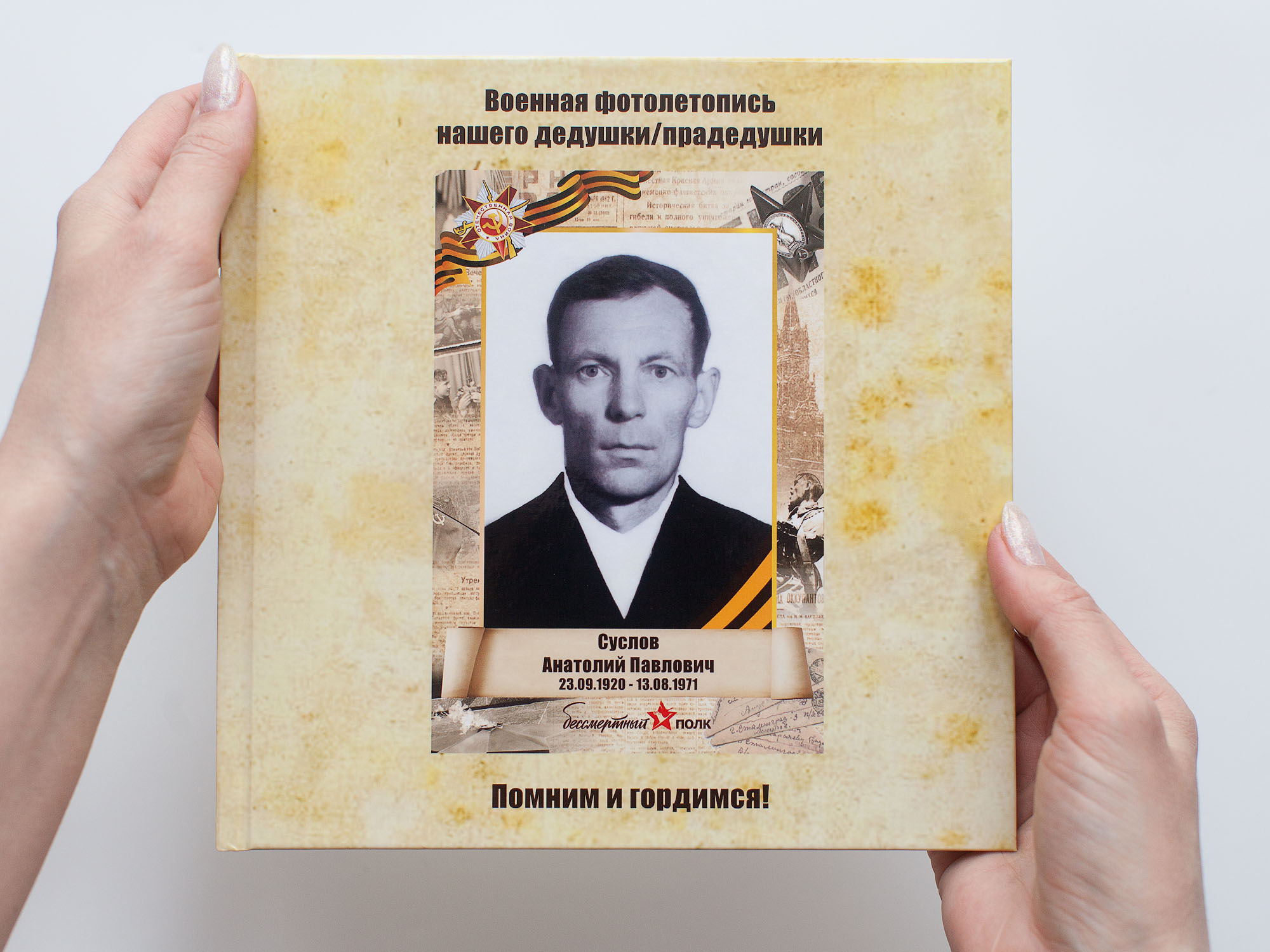 Квадратную фотокнигу держать женские руки. На обложке черно-белый портрет мужчины.