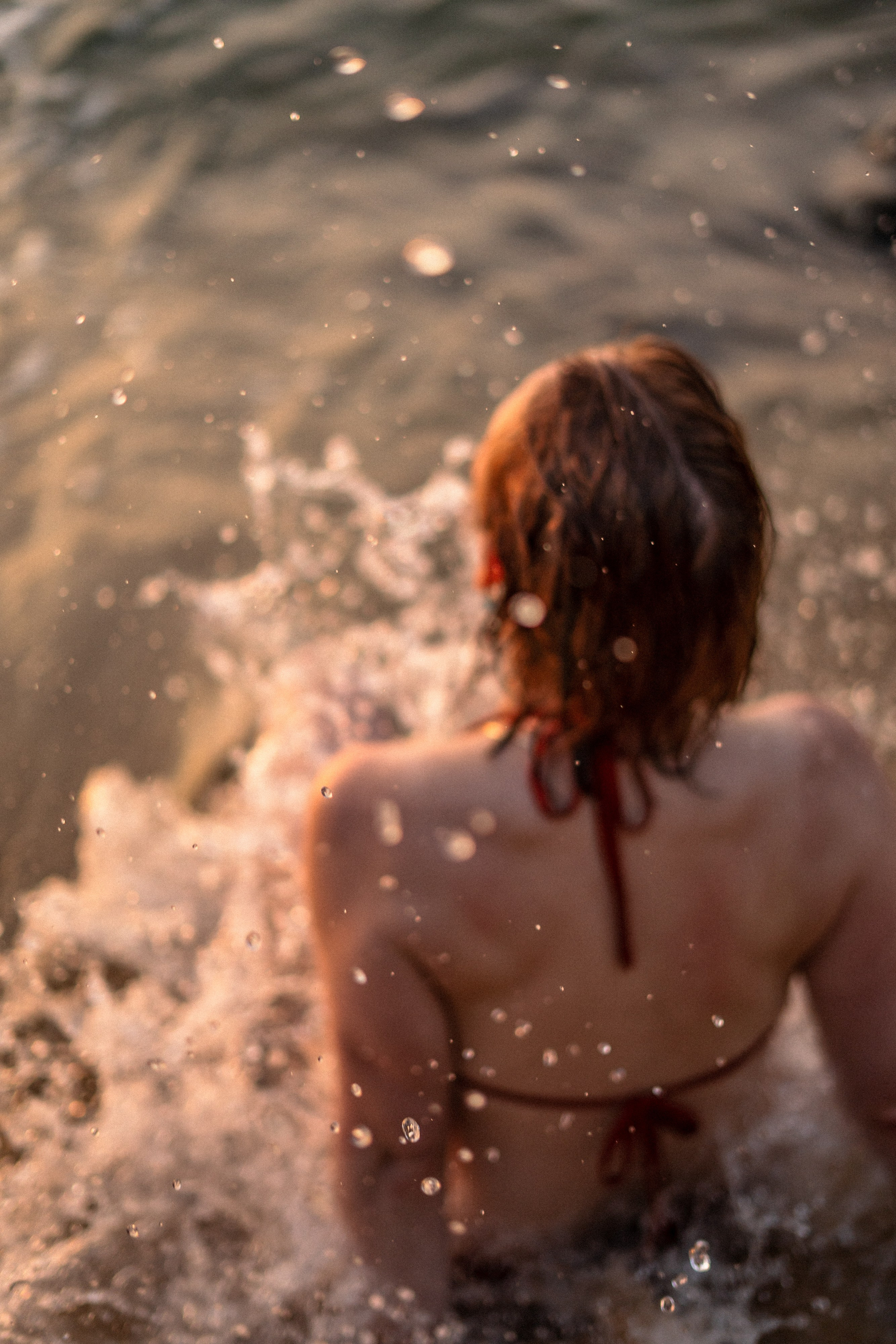 a girl in a red swimsuit against ocean waves and the sunset