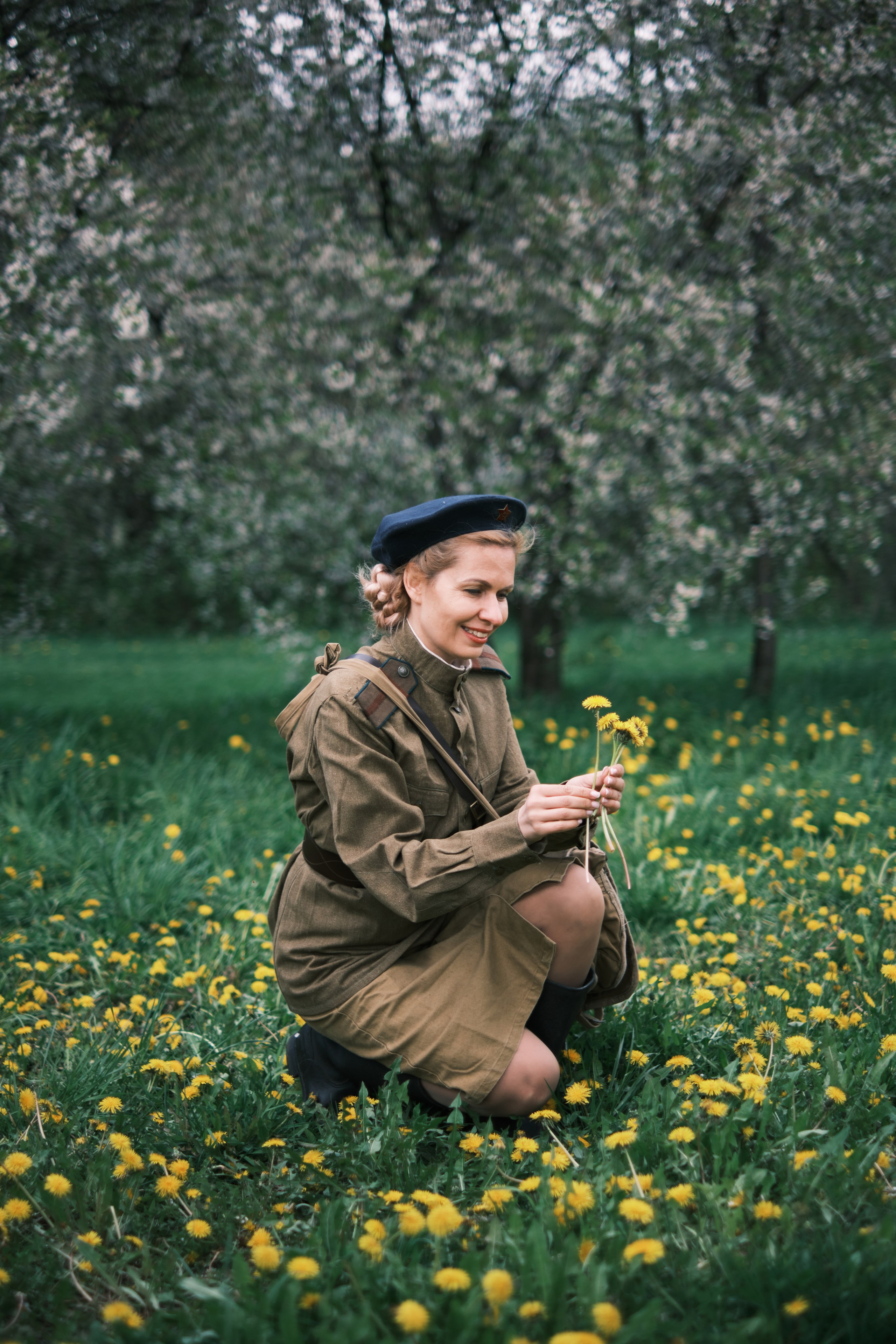 Девушка в военной форме собирает одуванчики