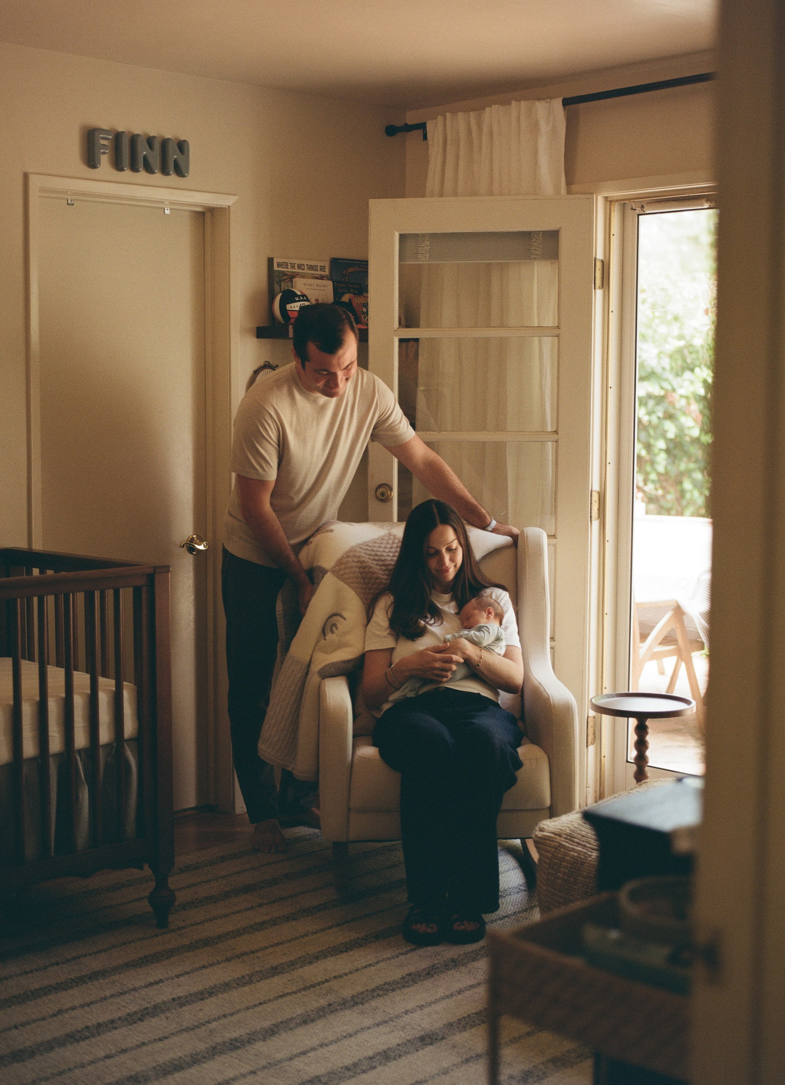 A man and a woman in the nursery, looking to their newborn baby boy, captured on film